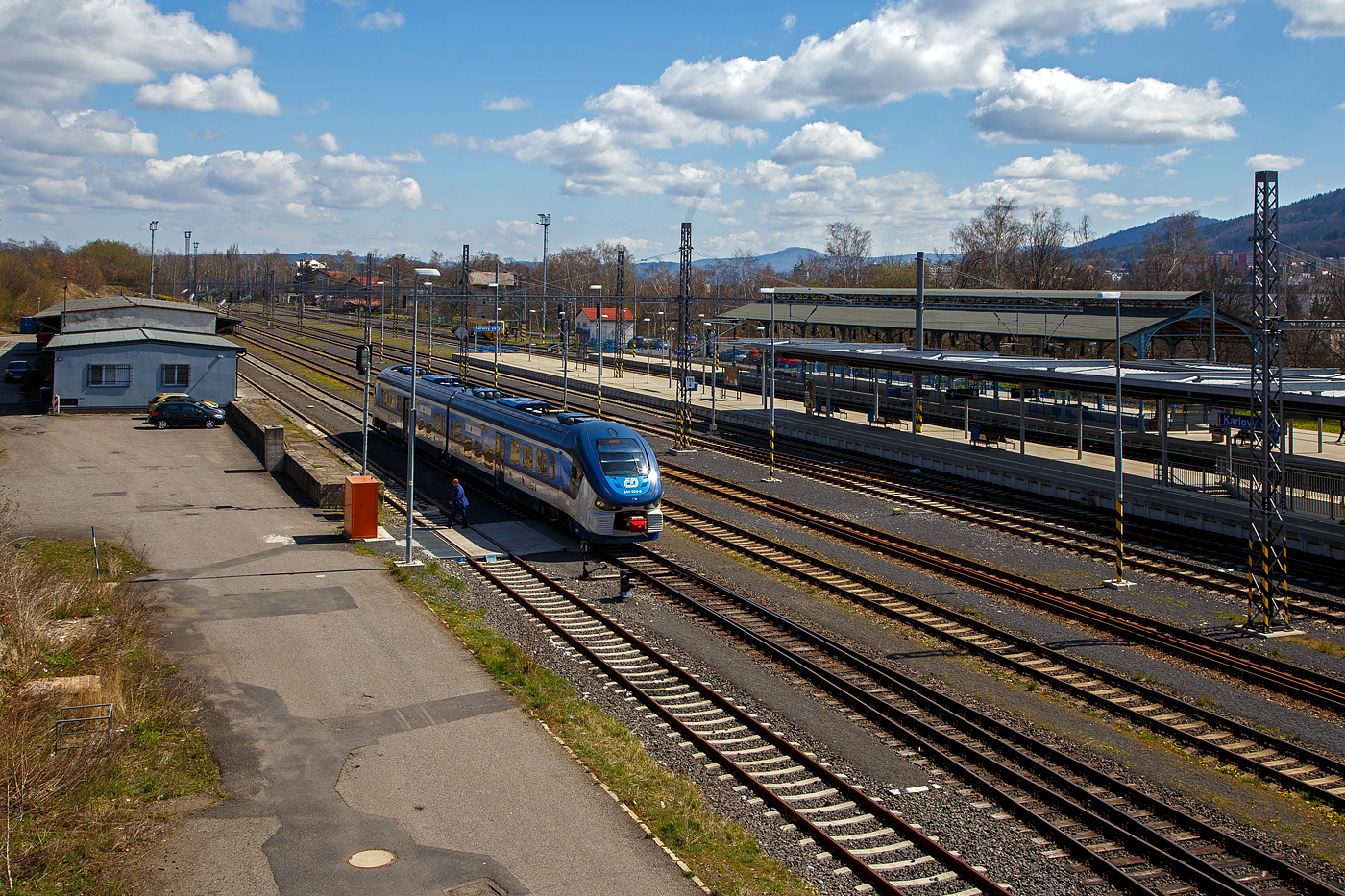 Blick von der Fußgängerbrücke/-überquerung auf den Bahnhof Karlovy Vary (Horním nádražím) / Karlsbad (Oberer Bahnhof), hier am 19.04.2023.

Vorne steht der ČD „RegioShark“ 844 024-0 (CZ-ČD 95 54 5 844 024-0), hinten rechts die denkmalgeschützte Bahnsteigüberdachung vom Kopfgleis 1.