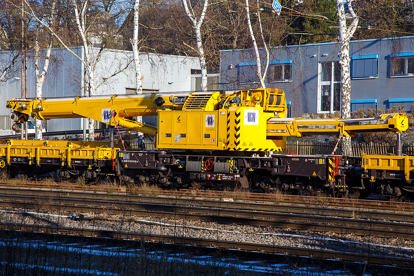 Der 125t Gleisbauschienenkran (Gleis- und Br�ckenbaukran) - KIROW Multi Tasker KRC 910, Kran 3 der MGW Gleis- und Weichenbau-GmbH & Co.KG (Berlin), Schweres Nebenfahrzeug Nr. D-MGWB 99 80 9419 025-8, ist in Transportstellung mit dem Schutzwagen gegenlastseitig (Gegengewichtwagen) 33 56 3999 005-0 SK-BUG (Gattung Res) und dem Schutzwagen auslegerseitig 33 80 3998 047-3 D-BUG (Gattung Res), am 30.10.2022 in Kreuztal abgestellt. Davor 3 zweiachsige Sch�ttgutwagen f�r Schotter der Gattung NS Fccpps der  Railpro.

Der Kran wurde 2018 von der Kirow Ardelt GmbH (Leipzig) unter der Fabriknummer  MT2017170871  gebaut und an die MGW geliefert.

Gut sieht man wie sich der Kranausleger auf den vorderen Schutzwagen und das Gegengewicht vom Kran auf den hinteren Schutzwagen, jeweils mittels eines Hydraulikzylinders abgest�tzt werden, dadurch werden in der Transportstellung die Achslasten vom Kran reduziert.

TECHNISCHE DATEN:
Eigengewicht: 104 t (in Transportstellung)
L�nge �ber Puffer: 13.000 mm (ohne Kranausleger), in Transportstellung mit den beiden Schutzwagen 13.000 mm + 2x19.900 mm = 52.800 mm
Achsanzahl: 8
Drehzapfenabstand: 8.000 mm
Drehzapfenabstand im Drehgestell 1 und 2: 2.300 mm
Achsabstand in den Einzeldrehgestellen: 1.100mm
Ergebene Achsabst�nde in m: 1,1 / 1,2 / 1,1/ 4,6 / 1,1 / 1,2 / 1,1
Achsfolge: 1'A'1A' A1'A1'
Lauf-  und Treibraddurchmesser: 730 mm (neu)
Achslast: 13,0 t (Streckenlast 8,0 t/m)
Zugelassene Streckenklasse: CE oder h�her
Dieselmotor: Wassergek�hlter Cummins 6-Zylinder Reihenmotor mit Partikel-Filter
Motorleistung: 200 kW
Not-Dieselmotor: Luftgek�hlter 2-Zylinder Viertakt-Dieselmotor mit Direkt-Einspritzung vom Typ Hatz 2 G 40 mit einer Leistung16 kW bei 3000 U/min
Fahrgeschwindigkeit im Zugverband: 100 km/h
Fahrgeschwindigkeit mit Eigenantrieb: 19 km/h
Zul. Anh�ngelast: 160 t
kleinster befahrbarer Radius: 80 m
Bremse: KE-GP mZ
Max. Tragf�higkeit abgest�tzt: 100 t
Max. Tragf�higkeit freistehend: 90 t
Max. Traglast bei max. Ausladung: 23 t
Max. Hakenh�he: 21.000 mm
