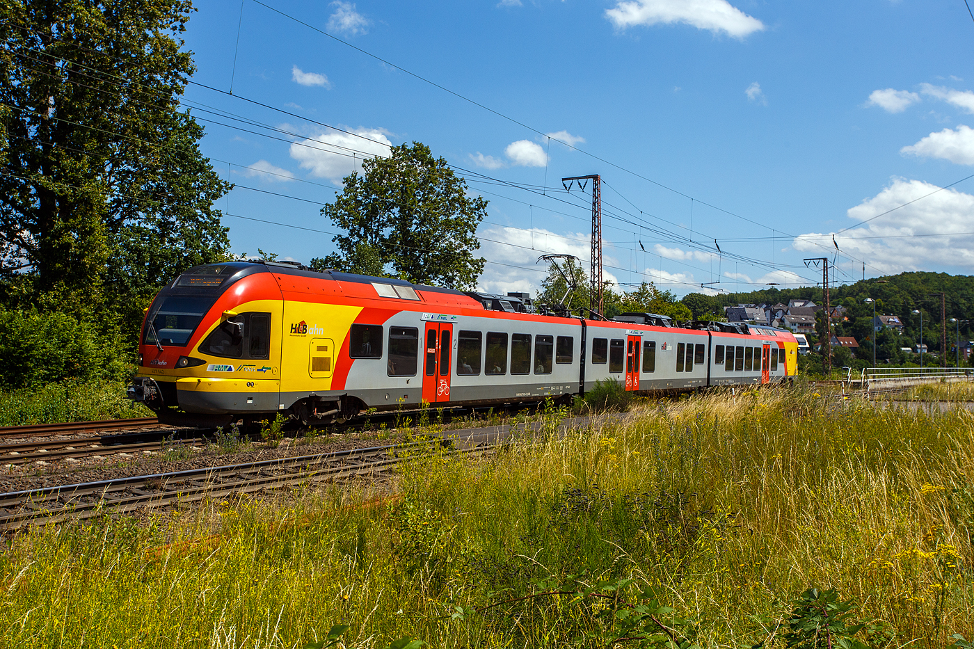 Der 3-teilige Stadler FLIRT 427 542 / 827 042 / 427 042 (94 80 0427 624-2 D-HEB / 94 80 0827 124-9 D-HEB / 94 80 0427 124-3 D-HEB) der HLB (Hessischen Landesbahn) fährt am 11 Juli 2024, als RE 99 „Main-Sieg-Express“ (HLB24512) Frankfurt am Main – Geißen – Siegen Hbf, durch Rudersdorf (Kreis Siegen) in Richtung Siegen.

Der Triebzug wurde 2010 von Stadler Pankow in Berlin unter den Fabriknummern 38623 bis 38625 gebaut und an die HLB geliefert

