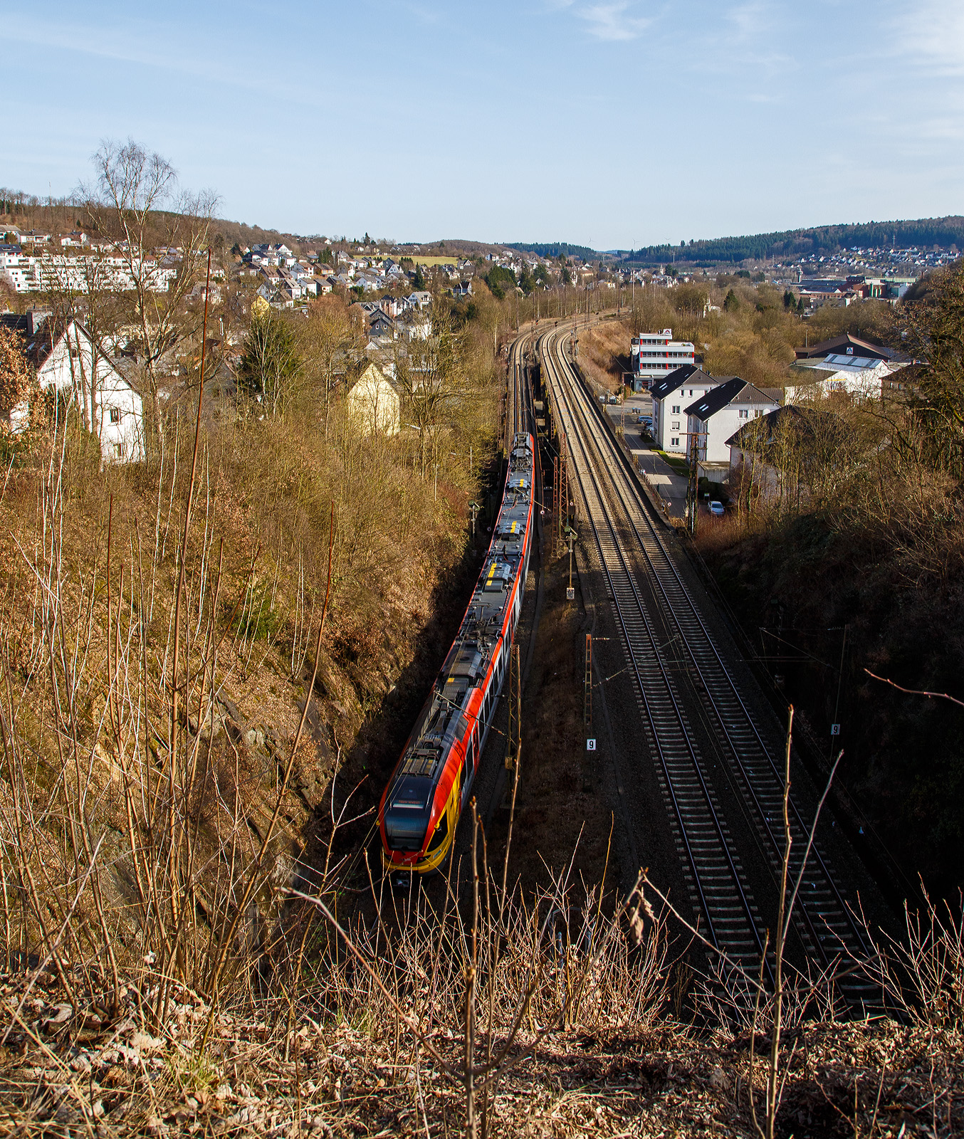 Der 5-teilige Stadler Flirt 429 050 / 429 550 der HLB (Hessischen Landesbahn) fährt am 12. März 2017, als RE 99  Main-Sieg-Express  (Siegen - Gießen - Frankfurt), in Richtung Gießen. Hier hat er gerade die eingleisige Röhre des Giersbergtunnels verlassen, rechts hinter den Bäumen kann man die ehemaligen Bahnhof Siegen-Ost erahnen. Links die eingleisige Strecke Siegen Hbf – Siegen-Ost und rechts die zweigleisige Strecke Siegen-Weidenau – Siegen-Ost.

Der Giersbergtunnel ist ein von 1912 bis 1915 erbauter Eisenbahntunnel Siegen. Namensgeber ist der 358 Meter hohe Giersberg im östlichen Stadtgebiet. Dieser wird in zwei getrennten Röhren durchquert. Ihr Bau wurde durch Liebold & Co AG aus Holzminden durchgeführt, das auch den Zuschlag für die Dillstrecke von Siegen-Weidenau bis Niederdielfen bekommen hatte. Bis 1914 waren rund 3.000 Arbeiter an dem Bauwerk tätig, mit Ausbruch des Ersten Weltkriegs ab Oktober 1914 nur noch rund 500 Arbeiter.

Lage und Führung der Tunnelröhren:
Durch die beiden Röhren des Giersbergtunnels führt zum einen die zweigleisige Strecke von Hagen über Siegen-Weidenau (KBS 400 „Ruhr-Sieg-Strecke“) nach Haiger (KBS 445 „Dillstrecke“), hier links im Bild. Diese zweigleisige Röhre hat eine Länge von 699 m und führt in nordsüdlicher Richtung. 

Zum anderen die eingleisige Strecke von Köln über den im Hauptbahnhof Siegen endenden (KBS 460 „Siegstecke“) nach Haiger bzw. weiter bis Gießen. Diese eingleisige Röhre hat eine Länge von 732 m und führt in westsüdlicher Richtung. Betrieblich gehören beide beiden Röhren zur KBS 445 „Dillstrecke“. Die Strecken der Röhren bilden an zwei getrennten Portalen auf der nordwestlichen Seite des Tunnels den Anschluss an zwei Schenkel eines Gleisdreiecks. Dabei überquert der zweigleisige Streckenabschnitt unmittelbar vor dessen eigenem Nordportal das Westportal der eingleisigen Strecke, diese beiden Portale sind nur ca. 60 m voneinander entfernt und stehen in einem Winkel von etwa 90 Grad zueinander. Daher zählt der Giersbergtunnel zu den Überwerfungsbauwerken. Die südöstlichen Mündungen beider Tunnelröhren (hier im Bild befinden wir uns oberhalb von ihnen) liegen in einem mit Bruchstein verkleideten Doppelportal nebeneinander im südöstlichen Hang des Giersbergs, um etwa zwei Meter in der Höhe zueinander versetzt. Beide Tunnelstrecken wurden am 1. Dezember 1915 in Betrieb genommen.

Betriebliche Aspekte:
Die eingleisige Strecke wird an Werktagen pro Stunde von durchschnittlich fünf Personenzügen befahren. Betrieblich ist die Strecke damit nicht überlastet, gilt aber überregional im Güterverkehr als Engpass im Schienennetz zwischen Köln und Frankfurt, hinzu kommt der Engpass Hauptbahnhof Siegen. Die Züge der Linie RE99 kreuzen beispielsweise kurz hinter der eingleisigen Strecke Richtung Haiger. Bei Verspätungen kann es passieren, dass der aus Frankfurt kommende Zug in Siegen Ost auf den Gegenzug warten muss. Ähnlich verhält es sich bei den IC-Zügen, die sich auf der anderen Seite des Tunnels im Hauptbahnhof kreuzen. Zusätzlich kommt es vor, dass zeitgleich noch Güterzüge auf Weiterfahrt in Siegen Ost oder Siegen Hbf warten müssen. Ein Ausbau auf Zweigleisigkeit ist aufgrund der engen Bebauung nur mit sehr hohen Kosten möglich.

Die zweigleisige Tunnelstrecke stellt eine direkte Verbindung zwischen der Dillstrecke und der nördlich davon gelegenen Ruhr-Sieg-Strecke her. Derzeit wird dieser Abschnitt nur vom Güterverkehr befahren. Bis zu ihrer Einstellung im Jahr 2002 fuhren über die zweigleisige Tunnelstrecke regelmäßig Interregio-Züge der Linie 22 (Münster-Frankfurt am Main), so war Siegen-Weidenau der eigentliche Fernbahnhof. Diese Relation ist ab Dezember 2021 als Intercity-Linie 34 wieder eingeführt worden, jedoch im Normalfall mit Bedienung von Siegen Hbf und Nutzung der eingleisigen Röhre. 
