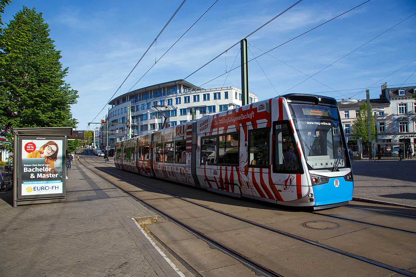 Der 6N2 Niederflur-Multi-Gelenktriebwagen 611, ein Vossloh Tramlink der RSAG (Rostocker Straßenbahn AG) hat am 14 Mai 2022 die Station Doberaner Platz erreicht.

Der 100porzentige Niederflur-Einrichtungs-Triebwagen wurde 2014 von Vossloh Espana (seit 2016 Stadler Rail Valencia), mit der Elektrischen Ausrüstung Vossloh Kiepe (Düsseldorf), gebaut und an die RSAG geliefert.

Die neuen 5-teiligen Multigelenk-Triebfahrzeuge vom Typ Tramlink 6N2 sind 100-prozentigen Niederflurstraßenbahnen, es sind Einrichtungstriebwagen die speziell auf die infrastrukturellen Gegebenheiten und die Charakteristik der Stadt Rostock zugeschnitten wurden.

Dank wassergekühltem Antrieb und der doppelten Federstufe zwischen den Radsätzen und den Wagenkästen sind die Straßenbahnen sehr leise und vibrationsarm und bieten einen hohen Fahrkomfort. Auf dem Fahrzeugdach befindliche Doppelschichtkondensatoren, sogenannte Supercaps, speichern die beim Bremsvorgang entstehende Energie, um diese anschließend wieder zum Anfahren und zur Begrenzung der Anfahrströme sowie für Heizung und Klimatisierung einzusetzen.

Die Innendecke der Straßenbahnen ist als zeitloses Fotodesign konzipiert. Durch dieses Fotodesign wird ein luftiges, großzügiges Raumgefühl geschaffen, welches auch bei hohem Fahrgastaufkommen für das Auge beruhigende Blickpunkte nach oben bietet. Der Innenraum der Straßenbahnen wird dadurch optisch vergrößert.

TECHNISCHE DATEN:
Spurweite: 1.435 mm
Fahrzeuglänge: 32.000 mm
Fahrzeugbreite: 2.650 mm
Fahrzeughöhe: 3.510 mm
Einstiegshöhe: 290 mm
Anteil Niederflur: 100 %
Leergewicht: 41,8 t
Türen: 6 (nur an der rechten Fahrzeugseite)
Sitzplätze: 71
Stehplätze: 139 (4 Pers./m²)
Raddurchmesser: 600 mm (neu) / 520 mm (abgenutzt)
Fahrdrahtspannung: DC 600 V; umschaltbar auf DC 750 V
Antrieb: 4 x 100 kW
Höchstgeschwindigkeit: 70 km/h
Zulassung: BOStrab
Besonderheiten: Energiespeicher zur Reduzierung der Anfahrströme

Die Straßenbahn Rostock ist neben der Straßenbahn in Schwerin die einzige noch bestehende in Mecklenburg-Vorpommern. Das Netz umfasst eine Streckenlänge von 35,6 Kilometer und 64 Haltestellen. Die erste Pferdebahn fuhr 1881 in der Innenstadt, die weiterhin das Zentrum des Netzes darstellt. Bis 2006 wurde das Netz nach und nach erweitert, sodass der Busverkehr nur noch die Hälfte des Verkehrsbedarfes abdecken muss. Seit 1992 kommen auch Niederflur-Gelenkwagen zum Einsatz. Seit etwa 2003 kann man bei sämtlichen Fahrten barrierefrei einsteigen.