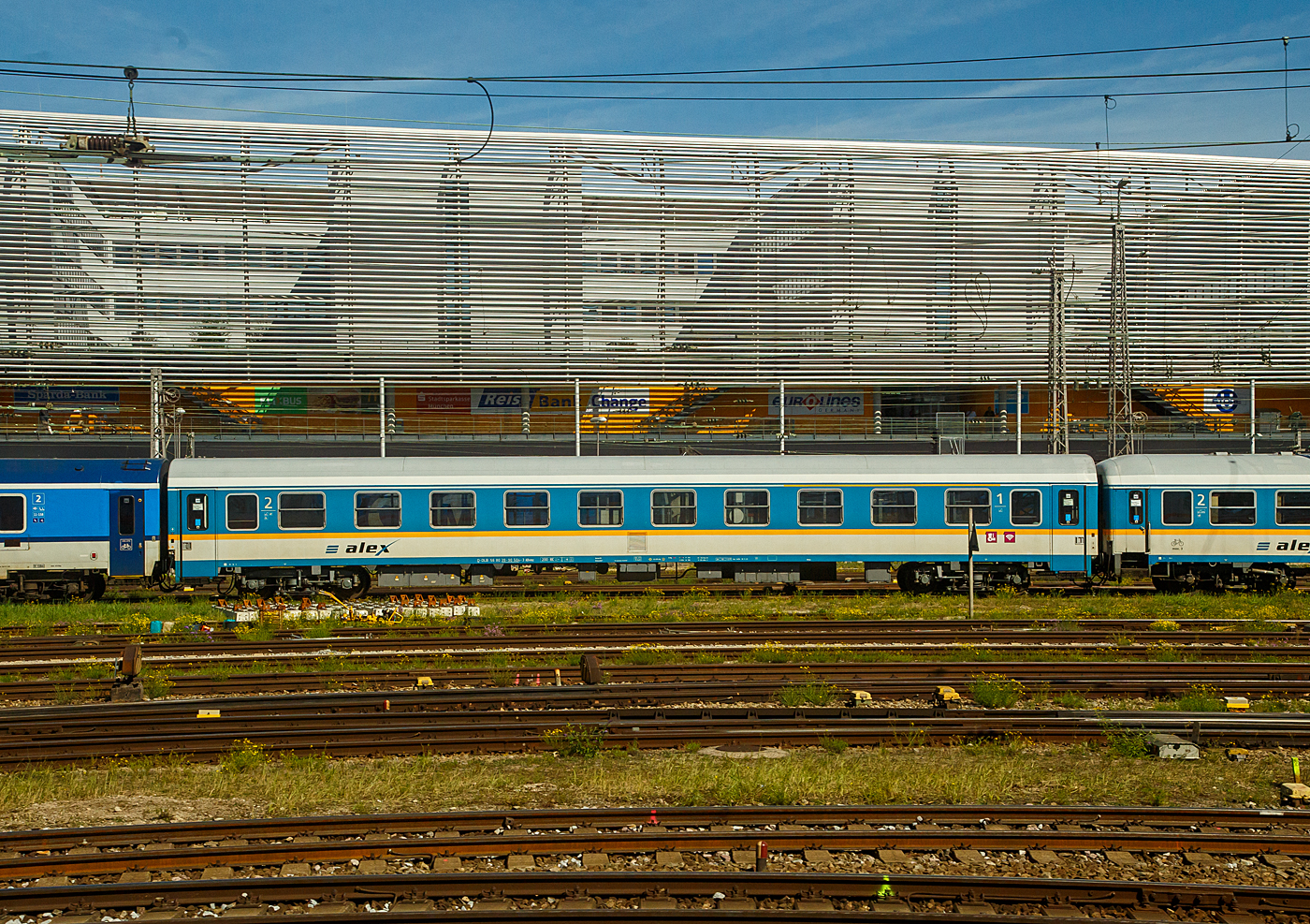 Der „alex“ Reisezugwagen der ersten/zweiten Wagenklasse 56 80 39-90 504-3 D-DLB der Gattung ABvmz (ex DB 51 80 10-90 504-1) des alex der DBL - Die Länderbahn GmbH ist am 13 September 2022, eingereiht in einem Zug, beim Hauptbahnhof München abgestellt.

Die Wagen der ehemaligen Gattung Amz 210 und (und wie hier) Amz 210.1 sind die jüngsten Fahrzeuge im Bestand des ALEX. Die Wagenserie entstand 1991 beim Waggonbau Bautzen (ehemals LOWA, später Deutsche Waggonbau AG (DWA), jetzt Bombardier) im Auftrag der Deutschen Reichsbahn. Sie entstanden nach dem Vorbild der Ame-Wagen des RAW Halberstadt (spätere Am 201) und den UIC-Z-Normen. Es wurden insgesamt 40 Wagen gebaut, die ab Werk im blauen Interregio-Farbschema lackiert waren, innen jedoch noch klassische Schnellzugwagen waren. Eingesetzt wurden sie bis 2002 im Interregioverkehr. Zum Schluss liefen sie teilweise noch in Regionalexpresszügen, im Jahr 2003 wurde diese Wagenserie (gerade einmal 12 Jahre alt!) komplett ausgemustert. 22 Wagen dieses Typs konnte die Regentalbahn von der DB kaufen, 2 Wagen wurden als Ersatzteilspender verwendet, so dass sich aktuell 20 Wagen im Bestand des ALEX befinden. 

Die Wagen besaßen ursprünglich 10 Abteile mit je 6 Sitzplätzen, beim ALEX wurden vier Abteile zur 1.Klasse mit je 5 Sitzplätzen, vier Abteile zur 2.Klasse mit je 6 Sitzplätzen, das zehnte Abteil entfiel zugunsten eines kleinen Mehrzweckbereichs. Einige Wagen laufen als rein zweitklassige Wagen.

Zur Einsetzbarkeit: Die Wagen mit den Ziffern 90 an 
der 7. und 8. Stelle der Wagennummer (wie dieser hier) sind mehrspannungsfähige RIC-Wagen, die Wagen mit den Ziffern 95 an dieser Stelle sind nur einspannungsfähig - die Versorgung der Zugsammelschiene ist nur mit der in Deutschland üblichen Spannung von 1000V und 16 2/3 Hz möglich.

TECHNISCHE DATEN:
Hersteller:  Waggonbau Bautzen (Umbau VIS Halberstadt)
Spurweite: 1.435 mm
Länge über Puffer: 26.400 mm
Wagenkastenlänge: 26.100 mm
Drehzapfenabstand: 19.000 mm
Achsstand im Drehgestell: 2.600 mm
Drehgestellbauart: GP 200-S-Mg
Leergewicht: 41 t
Höchstgeschwindigkeit: 200 km/h
Zulassungen: RIC (mehrspannungsfähig)
Sitzplätze: 20 in der 1. und 29 in der 2. Klasse, 2 Rollstuhlplätze
Abteile: 4 Abteile 1. Klasse; 4 Abteile 2. Klasse; 1 Mehrzweckabteil
Toiletten: 2, davon 1 behindertengerecht
Bremsbauart: KE-GPR-Mg
