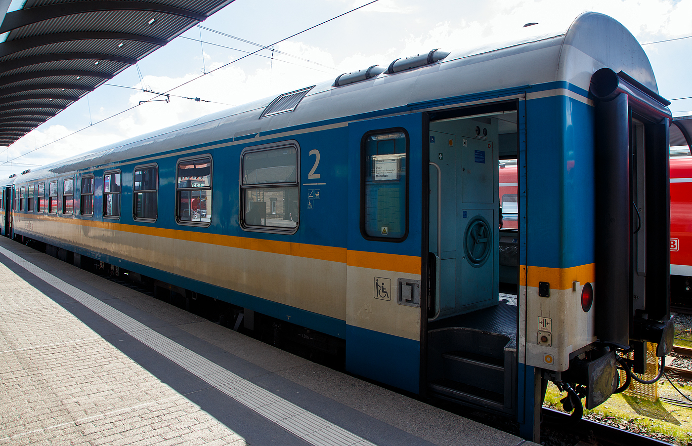 Der „alex“ Reisezugwagen der ersten/zweiten Wagenklasse 56 80 39-95 507-1 D-DLB, der Gattung ABvmz, des alex der DBL - Die L�nderbahn GmbH, steht am 21 April 2023, eingereiht in den RE 2 Hof – M�nchen, im Hauptbahnhof Hof.

Die meisten Wagen des alex geh�ren mit 17 Exemplaren der Bauart ABvmz an, welche durch Umbau aus Amz 210 bzw. dessen Umbauvarianten entstanden, dieser entstand aus einem Abteilwagen Am 203.0 der Deutschen Bundesbahn der Standardbauart UIC-x. 3 Abteile wurden zur 1. Klasse, 5 Abteile zur 2. Klasse, ein Mehrzweckraum eingerichtet, ein behindertengerechtes WC und eine Klimaanlage eingebaut. Die Wagen besa�en urspr�nglich 10 Abteile mit je 6 Sitzpl�tzen. Bei den ABvmz gibt es sowohl ein- als auch mehrspannungsf�hige Fahrzeuge, welche an der Heizungskennziffer zu unterscheiden sind. Die Wagen mit den Ziffern 90 an der 7. und 8. Stelle der Wagennummer sind mehrspannungsf�hige RIC-Wagen, die Wagen mit den Ziffern 95 (wie dieser hier) an dieser Stelle sind nur einspannungsf�hig - die Versorgung der Zugsammelschiene ist nur mit der in Deutschland �blichen Spannung von 1000V und 16 2/3 Hz m�glich.

Lebenslauf dieses Wagens:
• 1969 gebaut von LHB - Linke-Hofmann-Busch GmbH) in Salzgitter-Watenstedt (heute ALSTOM Transport Deutschland GmbH), geliefert im M�rz 1969 als D-DB 51 80 10-70 015-2 der Gattung Am 203.0 an die Deutsch Bundesbahn.
• 1988 umgebaut im PFA Weiden (Partner f�r Fahrzeugausstattung GmbH) zum D-DB 51 80 10-91 006-6 der Gattung Aim 260 (InterRegio-Wagen der 1. Klasse), sp�ter wurde er in die Gattungen  Aim 260.1 bzw. Aim 260.3 ge�ndert. 
• 1992 erfolgte beim WB Bautzen der Umbau zum D-DB 51 80 10-94 006-3 Aimz 261.6
• 1994 erfolgte der Umbau zum D-DB 51 80 10-95 507-9 Amz 210.0
• 2001 wurde er zum D-DB 51 80 20-95 507-7 Bomz 210.2
• 2002 wurde er ausgemustert und an die Regentalbahn verkauft, wurde umgebaut und erhielt die neue Nummer 56 80 39-95 507-1 D-RBG ABvmz, sp�ter 56 80 39-95 507-1 D-VBG, seit 2015 nun 56 80 39-95 507-1 D-DLB

TECHNISCHE DATEN:
Spurweite: 1.435 mm
L�nge �ber Puffer: 26.400 mm
Wagenkastenl�nge: 26.100 mm
Drehzapfenabstand: 19.000 mm
Achsstand im Drehgestell: 2.600 mm
Drehgestellbauart: GP 200-S-Mg
Leergewicht: 41 t
H�chstgeschwindigkeit: 200 km/h
Zulassungen: RIC (nur einspannungsf�hig)
Sitzpl�tze: 15 in der 1. und 34 in der 2. Klasse, 2 Rollstuhlpl�tze
Abteile: 3 Abteile 1. Klasse; 4 Abteile 2. Klasse; 1 Mehrzweckabteil
Toiletten: 2, davon 1 behindertengerecht
Bremsbauart: KE-GPR-Mg