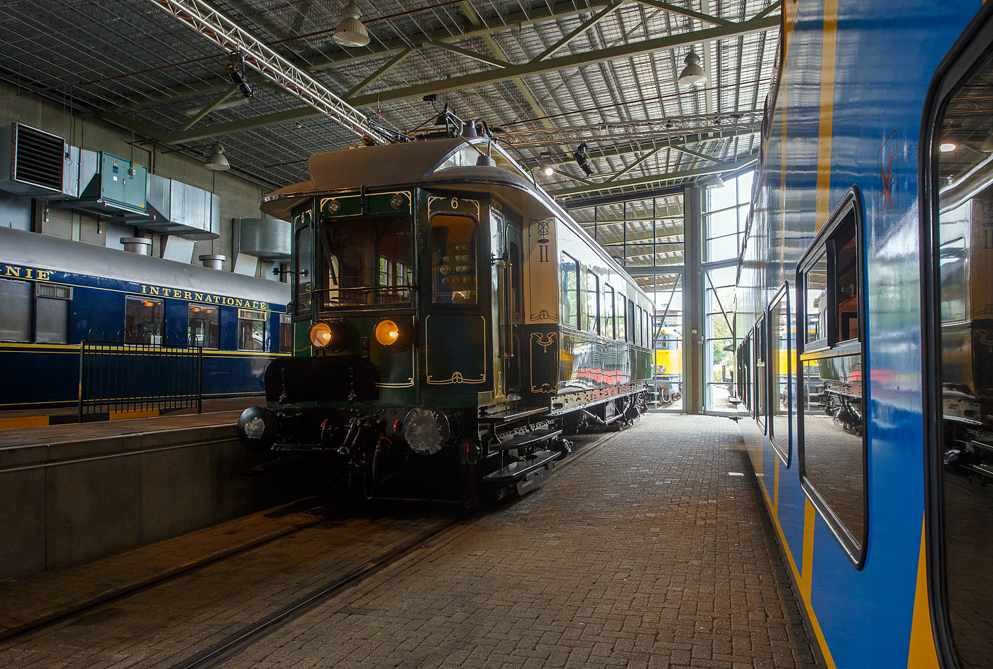 Der älteste elektrische Triebwagen der Niederlande, der ZHESM 6 mBC der Zuid-Hollandsche Electrische Spoorweg-Maatschappij (Südholländischen Elektrischen Eisenbahn-Gesellschaft), später NS BC 9911, am 24 Juni 2025 im Het Spoorwegmuseum (bis 2005 NSM - Nederlands Spoorwegmuseum / Niederländischen Eisenbahnmuseum) in Utrecht im ehemaligen Bahnhof Maliebaan.  

Der Triebwagen wurde 1908 von der Koninklijke Fabriek van Rijtuigen en Spoorwagens J.J. Beijnes (Königliche Fabrik für Kutschen und Eisenbahnwagons J.J. Beijnes) in Haarlem gebaut und bei der Südholländischen Elektrischen Eisenbahn-Gesellschaft mit der Nummer 6 (Serie 1 – 1) in Dienst gestellt. Die ursprüngliche elektrische Ausrüstung war von Siemens Schuckert (Berlin), die aber 1927 von Heemaf (Hengelo) ersetzt wurde.

Die Triebwagen basierten auf einem amerikanischen Design. Sie waren in Creme (oben) und Grün (unten) lackiert und mit einem Jugendstildekor versehen. Es gab 24 Sitzplätze (Samtpolstersitze) der 2. Klasse und 49 (Holzbänke) der 3. Klasse. Die Triebwagen wurden mit einer Anlage für 10 kV Einphasenwechselstrom in Dienst gestellt. In einem Drehgestell waren die beiden Fahrmotoren untergebracht, das andere Drehgestell enthielt den Luftkompressor, der unter anderem für die Bremse zuständig war. Die mBCs bedienten den Nahverkehr Rotterdam Hofplein – Den Haag HS – Scheveningen in der Regel als Zwei-Wagen-Zug.

Im Jahr 1921 ging das Rollmaterial in die neue NS (Nederlandse Spoorwegen) über. Die Nummer 6 wurde mehrfach umgebaut und um nummeriert. Im Jahr 1926 wurden die 23 ZHE-Triebwagen und 17 Mittelwagen auf 1500 Volt Gleichstrom umgerüstet. Der 6er erhielt versuchsweise eine Neuinstallation von Siemens und erhielt wieder das ursprüngliche Zweiklassensystem. 

Der Versuch wurde 1927 beendet, danach wurde der ET erneut mit einer anderen Installation, diesmal von Heemaf, ausgestattet. Außerdem erhielt er nun 4 Motore á 165 KW (225 PS), nun hatte er die Achsfolge Bo´Bo´ (anstatt Bo´2´), so wurde die Leistung erheblich gesteigert. Zudem erhielt er nun die Bezeichnung BC 9011, entsprechend der restlichen Serie BC 9001–9010.

Im Jahr 1930 wurde die mechanische Kilometererfassung eingeführt, die es erforderlich machte, allen Triebfahrzeugen eine eigene Nummernserie zuzuordnen. Für unsere ZHE-ler wurde dies zu BC 9901 – 9911. BC 9011 wurde jetzt zu BC 9911. Die Farbe wurde in den 1930er Jahren durch ein komplett grünes Farbschema ersetzt.

Im Jahr 1944 wurde BC 9911 mit den meisten anderen ZHE-Rollmaterial nach Deutschland gebracht. Nach der Befreiung kehrten die meisten von ihnen in die Niederlande zurück, aber 4 Triebwagen und 1 Waggon der ehem. ZHE blieben vermisst. Die verbliebene und zurückgegebene Ausrüstung hatte erheblichen Schaden genommen. Nur der BC 9911 (ex Nummer 6) war 1946 noch einsatzfähig. Einige kaputte Fenster wurden notdürftig mit Holz und kleinen Glasscheiben verschlossen. Zusammen mit dem Steuerwagen C 8043 bildete er den einzigen ZHE-Zug, der auf der Hofplein-Linie verkehrte.

Ab 1947 wurden auf der Hofplein-Linie nur noch Stromlinienfahrzeuge eingesetzt. Der BC 9911 wurde zum Dienstfahrzeug und transportierte Waggons mit Lagergütern zwischen der Zentralwerkstatt in Haarlem und dem Lijnwerkplaats Leidschendam, blieb jedoch unverändert. Erst später im Jahr 1949 erhielt der Wagen die Dienstnummer 157991.

1957 wurde der technisch vollständige Wagen dem Eisenbahnmuseum gespendet. 1994 fand in der Hauptwerkstatt in Haarlem eine umfangreiche Restaurierung statt, bei der auch das Fahrgestell nach einem früheren Unfall repariert wurde. Dabei musste die elektrische Verkabelung entfernt werden. Nach der Restaurierung wurden die ursprünglichen Farben und Jugendstildekorationen wiederhergestellt. Da der Wagen nicht mehr aus eigener Kraft fahren durfte und nur mit begrenzter Geschwindigkeit transportiert werden konnte, wurde das Antriebssystem nicht repariert. Allerdings sind noch alle elektrischen Komponenten aus dem Jahr 1926 vorhanden.

Der Triebwagen gilt als eines der Highlights des Eisenbahnmuseums.

TECHNISCHE DATEN:
Spurweite: 1.435 mm (Normalspur)
Länge über die Puffer:	18.600 mm
Achsfolge:	Bo'Bo, ursprünglich Bo'2' (1908 bis1927)
Höchstgeschwindigkeit: 80 km/h
Antriebmotoren: 4, ursprünglich 2
Leistung von 1908 bis 1927: 2 x 132 kW (2 x 180 PS)  
Leistung ab 1927: 4 x 165 KW (4 x 225 PS)
Stromsystem: 1.500 V DC, ursprünglich 10 k V 25 Hz Einphasenwechselstrom
Eigengewicht: 62 t
Sitzplätze: 24 der 2. Klasse (Samtpolstersitze) und 49 der 3. Klasse (Holzbänke)
