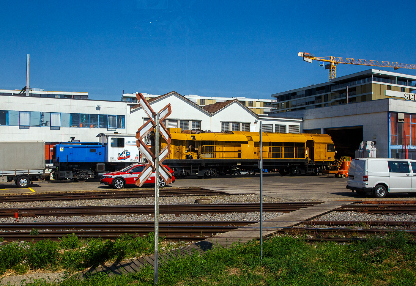 Der Diesel-Rangiertraktor (Thermischen Traktor) Tm Nr. 3 „HUSKY“ (40 85 97 70 001-9) der Scheuchzer SA mit einem Teilstück einer Hochleistungsschleifmaschine Grizzly am 07 September 2023 vor der Werkshalle der Scheuchzer SA in Bussigny (VD / Kanton Waadt). Bild aus einem Zug heraus.

Diese Diesellok ist eine von vier Loks vom Typ DE-SF 1 bzw. 3 die 1970/1972 von der Lokomotiven- und Maschinenfabrik Gmeinder & Co. GmbH in Moosbach (D), für die Schweizer Scheuchzer SA in Bussigny gebaut wurden. Diese wurde 1972 von Gmeinder unter der Fabriknummer 5486 gebaut. Sie ist auch die letzte bei Scheuchzer noch vorhandenen Loks dieses Typs und wird auf dem Firmengelände für Rangierarbeiten eingesetzt. Die ursprüngliche Aufgabe der Tm war der Vor- und Nachspann von zwei Schienenschleifzügen MR I und II der Firma Scheuchzer, welche diese selbst entwickelt und gebaut hatte. Diese waren von 1971 bis 1988 im Einsatz.

Übrigens, die Scheuchzer SA betreibt ausschließlich normalspurige Fahrzeuge, die mehrheitlich den UIC-Normen entsprechen.

TECHNISCHE DATEN der Lok:
Typ: Gmeinder DE-SF3
Spurweite: 1.435 mm (Normalspur)
Achsfolge: B (2 Achsen)
Antriebsart: dieselelektrisch 
Länge über Puffer: 7.650 mm
Achsabstand: 3.000 mm
Eigengewicht: 23.000 kg
Stundenleistung: 250 kW
Höchstgeschwindigkeit: 60 km/h (geschleppt 80 km/h)
Minimaler befahrbarer Kurvenradius: R 100 m
Bremse: Frein O-P