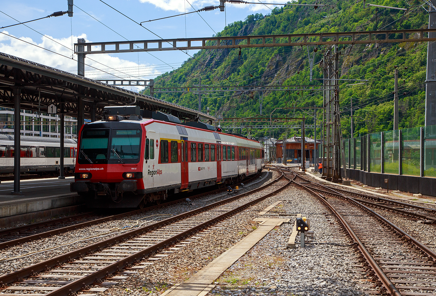 Der dreiteilige NPZ Domino RA12 der RegionAlps (ex SBB RBDe 4/4) erreicht am 25.05.2023 als Regio (St-Gingolph–St-Maurice –Martigny–Sion–Brig), Steuerwagen voraus, seinen Zielbahnhof Brig.

Der NPZ Domino besteht aus:
1./2. Klasse Steuerwagen ABt NPZ DO RA 50 85 39-43 948-1 CH-RA
Modernen 2.Klasse INOVA-Zwischenwagen mit Niederfluranteil B NPZ DO RA 50 85 29-43 407-0 CH-RA
und dem 
Triebwagen RBDe 560 DO RA 94 85 7 560 412-9 CH-RA, ex SBB RBDe 560 010-1 (Umbau 2009).

Die Regionalps (RA) ist ein Eisenbahnverkehrsunternehmen im Kanton Wallis, mit Sitz in Martigny hat. Eigentümer derim Jahr 2003 gegründete Gesellschaft  sind die Schweizerischen Bundesbahnen (SBB) mit 70 %, die Transports de Martigny et Régions (TMR) mit 18 % und der Kanton Wallis mit 12 %. Die RA betreibt den Regionalverkehr vor allem im Rhonetal zwischen dem Ostufer des Genfersees und Brig. Inzwischen gehören Regionalps 16 dreiteilige NPZ Domino (Trieb-, Zwischen- und Steuerwagen ex SBB) und 4 RABe 525 NINA (ex TMR).

Als RBDe 4/4 wurden die Triebwagen der Schweizerischen Bundesbahnen (SBB) bezeichnet, die ab 1984 für die als Neuer Pendelzug (NPZ) bezeichneten Regionalzugskompositionen mit den dazugehörenden Steuerwagen angeschafft wurden. Sie tragen seit 1990 die Baureihenbezeichnung RBDe 560. Aus Kostengründen wurde damals auf die Beschaffung neuer Zwischenwagen verzichtet, verwendet werden stattdessen umgebaute Einheitswagen (EW I und EW II).

Die meisten von 1987 bis 1996 gebauten Fahrzeuge RBDe 560, 561 und 568 durchliefen 2008 bis 2013 ein Komplett-Modernisierungsprogramm. Aus aufgearbeiteten Trieb- und Steuerwagen sowie neu beschafften Zwischenwagen entstanden Regionalverkehrs-Kompositionen mit der Bezeichnung «Domino». Die Triebwagen werden dabei einheitlich als RBDe 560 (94 85 7 560 XXX-X) bezeichnet. Sie können in Vielfachsteuerung verkehren.

TECHNISCHE DATEN (Komposition RBDe 560, B und ABt) :
Spurweite:  1.435 mm (Normalspur)
Achsformel:  Bo’Bo’ +2´2´+2´2´
Länge über Puffer:  25.000 mm / 24.700 mm / 25.000 mm
Drehzapfenabstand: 17.600 mm / 18.900 mm /17.600 mm
Achsabstand im Drehgestell: 2.700 mm (ZW 2.500 mm)
Treib- und Laufraddurchmesser: 950 mm
Höhe:  3.750 mm
Breite:  2.860 mm
Dienstgewicht:  72 t (Triebwagen) + 36 t (ZW) + 38 t (Steuerwagen)
Höchstgeschwindigkeit: 140 km/h
Dauerleistung:  1.650 kW (2.250 PS)
Anfahrzugkraft:  182 kN
Dauerzugkraft: 78 kN
Anzahl Fahrmotoren: 4
Stromsystem:  Wechselstrom 15 kV 16,7 Hz
Sitzplätze: 54 (TW) / 60 (ZW) / 12+60 (SW) = 186 (12 in der 1. Klasse)
Ladegewicht: 0,3 t (Triebwagen)
Kupplungstyp: Schraubenkupplung