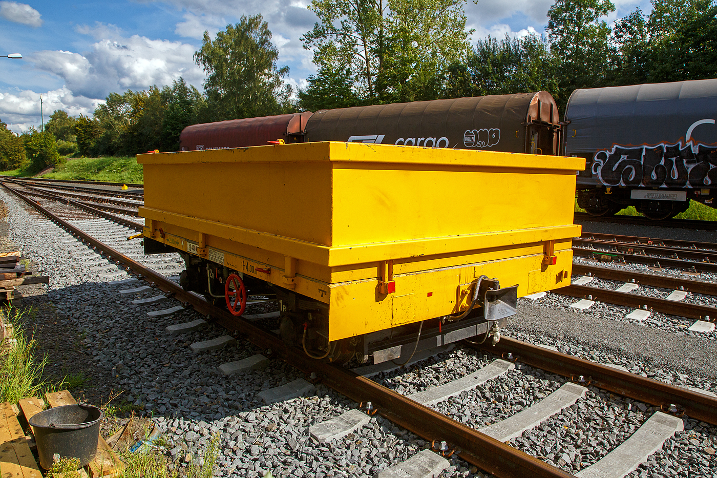 Der Gleiskraftwagenanh�nger GKW-A, Kleinwagen-Nr. D-BMSS 99 80 9750 489-3 der BMS Schlage (Lieske) ist am 26.08.2023 in Herdorf auf dem Rbf der KSW, Betriebsst�tte FGE -Freien Grunder Eisenbahn, abgestellt. 

Der Kleinwagenanh�nger  34.1 Typ GKW-A -H 25 (der BA 341) wurde 1962 vom RAW Sch�nweide gebaut. Von der f�nfstelligen Fabriknummer kann ich leider nur die letzten drei Ziffern (??392) genau erkennen. Bei diesem Anh�nger wurden die Seiten- und Stirnwandklappen gegen einen aufgesteckten Aufsatzrahmen getauscht.

Wie auch die Deutsche Bundesbahn (DB) setzte die Deutsche Reichsbahn (DR) in der DDR Kleinwagen mit eigenem Antrieb und passende Anh�nger im Streckenunterhalt ein. W�hrend die Bundesbahn die Abk�rzung Klv und Kla (Kleinwagen mit Verbrennungsmotor bzw. -Anh�nger) verwendete, k�rzte die DR mit den Buchstaben GKW f�r Gleiskraftwagen bzw. GKW-A f�r Gleiskraftwagen-Anh�nger ab. 

TECHNISCHE DATEN:
Spurweite: 1.435 mm (Normalspur)
L�nge �ber Kupplung: 4.000 mm
Achsabstand: 2.000 mm
Laufraddurchmesser: 560 mm
Eigengewicht: 3.400 kg 
Nutzlast: 8 t (urspr�nglich lt. Fabrikschild 9.500 kg) 
Zul. Geschwindigkeit (Hg): 60 km/h
Handbremse: Ja
