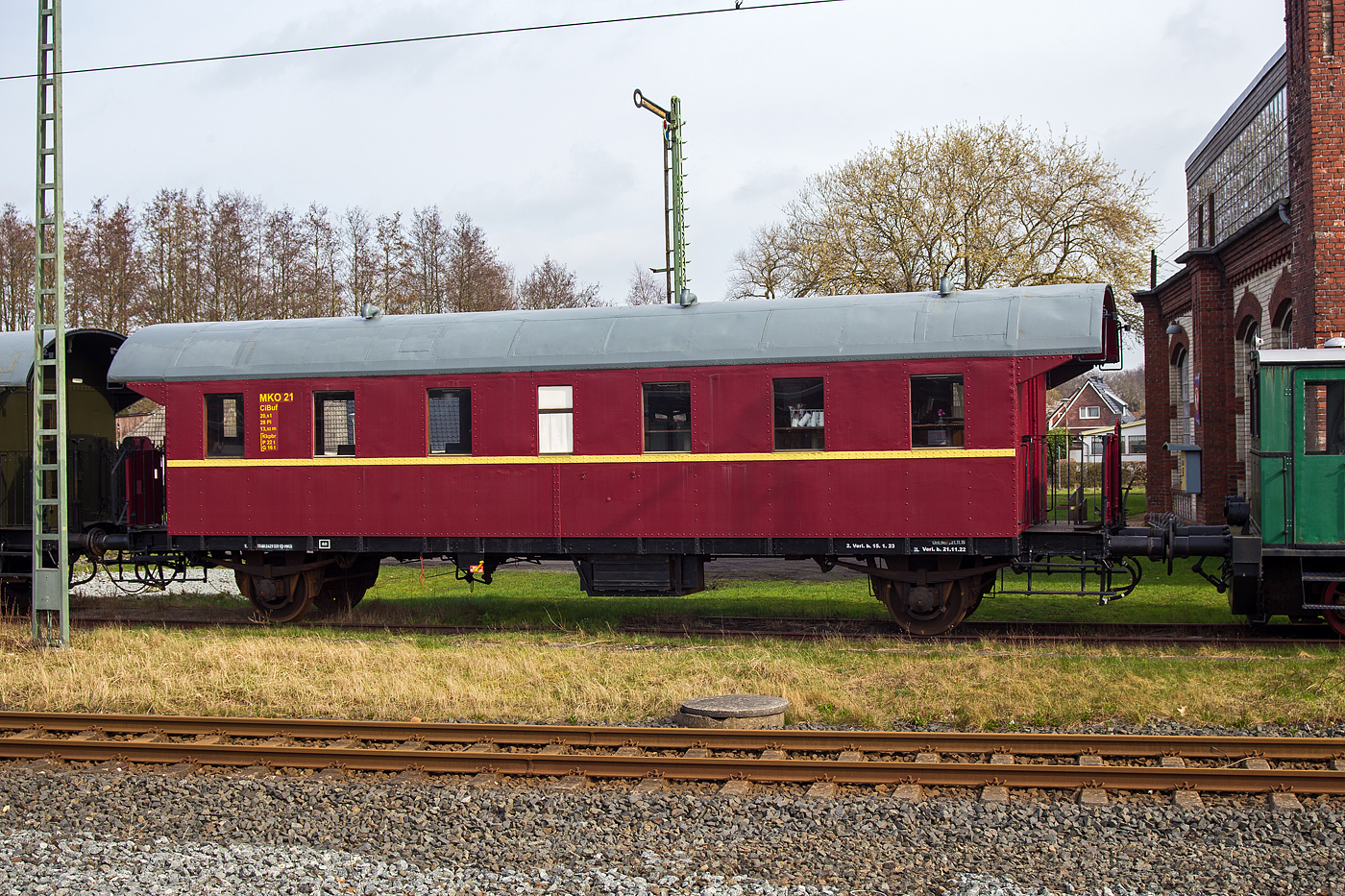 Der MKO 21 – Buffetwagen CiBuf (ex Ci-28), heutige UIC-Nr. 75 80 2429 331-1 D-MKO, eine zweiachsige Donnerb�chsen, der MKO - Museumseisenbahn K�stenbahn Ostfriesland e. V., am 14 M�rz 2024 auf dem Museumsareal in Norden, gleich neben dem Bahnhof Norden.

Ende der 1920er Jahre beschaffte die Deutsche Reichsbahn Gesellschaft (DRG) eine Serie neuer zweiachsiger Sitzwagen mit offenen Endb�hnen und �berg�ngen. Sie entstanden in genieteter Ganzstahlbauweise. Die Wagen entwickelten bauartbedingt ein wohl etwas dr�hnendes Fahrger�usch, das ihnen den Spitznamen „Donnerb�chsen“ einbrachte. Nach dem Ausscheiden der Wagen aus dem Personenzugdienst wurden viele zu Bauzugwagen umgebaut und fristeten danach vielerorts als Bahnhofswagen ihr Dasein.

Bei diesem Wagen handelt es sich urspr�nglich um ein 3. Klasse- Fahrzeug. Der Wagen wurde in mehrj�hriger Arbeit von den Vereinsmitgliedern aufgearbeitet. Nach vorsichtiger Entfernung etlicher Farbschichten konnten die Originalanschriften wieder freigelegt und somit die Wagennummer ermittelt werden. Der Innenraum erhielt je zur H�lfte Holzb�nke nach altem Muster und eine Buffetausstattung. 1993 wurde der Wagen in den Einsatzbestand eingereiht.

TECHNISCHE DATEN:
Hersteller: MAN
Baujahr: 1928
Spurweite: 1.435 mm (Normalspur)
Bauart: Ci-28 (CiBuf)
Wagennummer: DRG Ci 84 024, DB 60 355
Anzahl der Achsen: 2
L�nge �ber Puffer: 13.920 mm
Wagengewicht: 20.600 kg
Sitzpl�tze: 28
