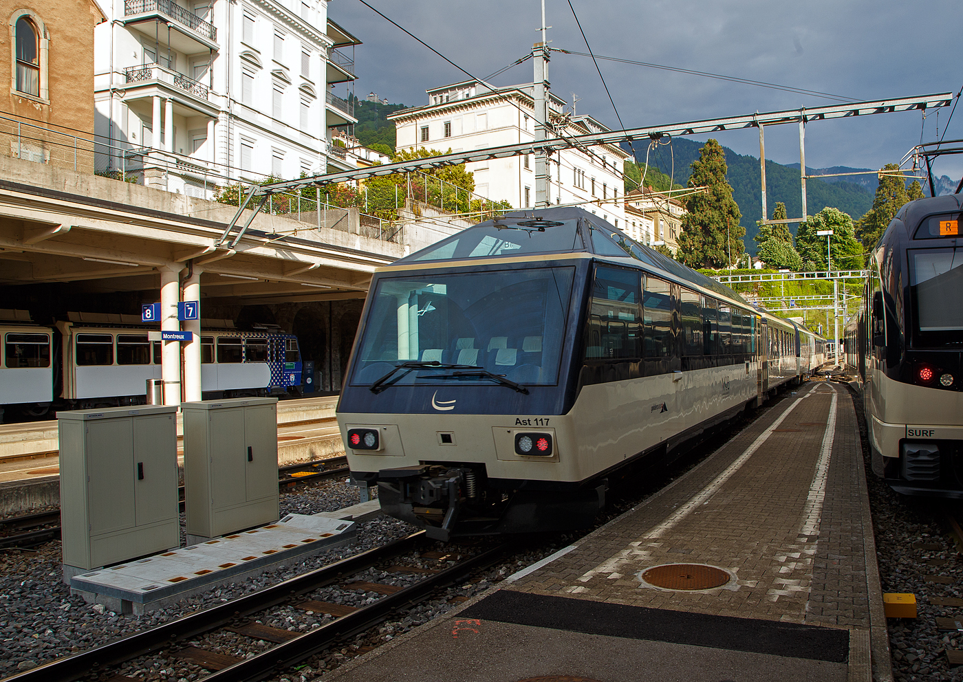 Der MOB GoldenPass-Zug R 2232 nach Zweisimmen verl�sst am 26 Mai 2023 den Bahnhof Montreux, am Zugschluss der vierachsige MOB 1.Klasse Panorama-Steuerwagen Ast 117 (ex Arst 117).

Befl�gelt durch den Erfolg des “Panoramic-Express” nahm die MOB 1986 eine dritte Komposition in Betrieb, welche aber gegen�ber den beiden vorherigen nur die erste Wagenklasse f�hrte und von zwei Panorama-Steuerwagen an beiden Zugenden gesteuert wurden. Die beiden Arst 116/117 erhielten dabei die F�hrerst�nde aus den dazwischen eingereihten Triebwagen BDe 3005/3006, welche ebenfalls farblich an den Zug angepasst wurden. Der Barwagen Ars 115 komplettierte den Paradezug der MOB. Ganze Frontseite steht den (VIP) Reisenden als Aussichtsabteil zur Verf�gung. 

TECHNISCHE DATEN:
Hersteller: R&J / MOB / SIG
Spurweite: 1.000 mm (Meterspur)
Achsanzahl: 4 (in 2 Drehgestellen)
L�nge �ber Puffer: 17.290 mm 
Wagenkastenl�nge: 16.470mm
H�he: 3.700 mm
Breite: 2.650 mm
Drehzapfenabstand: 11.350 mm 
Achsabstand im Drehgestell: 1.800 mm
Drehgestell Typ: SIG- Torsionsstab
Laufraddurchmesser: 750 mm (neu)
Eigengewicht: 20  t 
H�chstgeschwindigkeit: 100 km/h
Sitzpl�tze: 8 VIP-Pl�tze hinter der Frontscheibe und 25 in der 1. Klasse  
WC: 1

Quellen: x-rail.ch 
