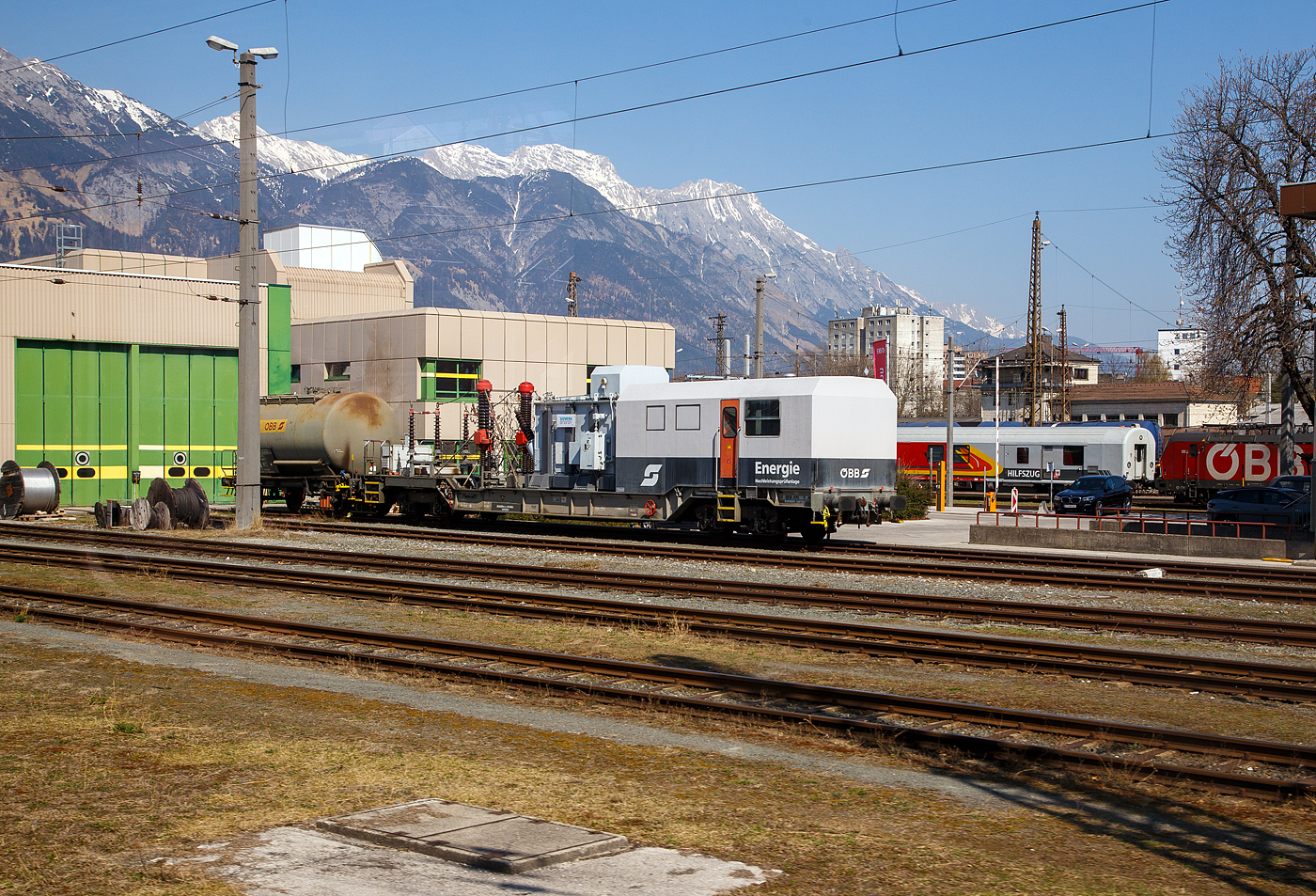 Der �BB Pr�fwagen HPA bzw. Energie Hochleistungspr�fanlage (auf Tieflader-Wagen) A-�BB 80 81 972 6 001-7 der �BB-Infrastruktur AG, abgestellt am 28 M�rz beim Depot in Innsbruck, hinten der �BB Hilfszug-Wagen A-�BB 51 81 99 75 004-4. Die Aufnahme ist aus einem EC heraus.

Hochspannungstests an der Eisenbahn-Infrastruktur
Der Waggon f�r Hochspannungstests (HPA), ist eine mobile Pr�feinheit, die speziell f�r die Instandhaltung von Komponenten der Eisenbahn-Infrastruktur entwickelt wurde. Damit wird die Funktionsf�higkeit und Sicherheit der elektrischen Infrastruktur an verschiedenen Stellen in ganz �sterreich �berpr�ft. 

Das Energienetz der �BB besteht aus Kraftwerken, Frequenzumrichtern, Leitstellen, Bahnstromleitungen und Umspannwerken, also viele Faktoren die �berwacht und gewartet werden sollten. Das Bahnstromnetz der �BB-Infrastruktur AG ist �ber 2.000 Kilometer lang und arbeitet mit einer Frequenz von 16,7 Hz. Das Netz verteilt den Strom von den Kraftwerken und Frequenzumrichtern auf mehr als 60 Umspannwerke. Diese transformieren die Spannung von 55 oder 110 kV der Bahnstromleitungen auf 15 kV f�r die Oberleitung zur Versorgung der Bahn.