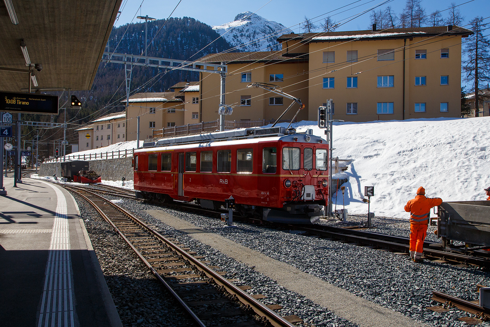  Der RhB Triebwagen ABe 4/4 II 46 wird am 22.03.2023 in Pontresina an einen Bauzug gekuppelt.

Der Triebwagen 46 ist zum Erhalt als historisches Fahrzeug vorgesehen. Im M�rz 2021 erhielt er durch den Club 1889 seine historische Lackierung mit goldenem Zierstreifen zur�ck.

Als ABe 4/4 II werden bei der Rh�tischen Bahn (RhB) die auf der Berninabahn eingesetzten Elektrotriebwagen mit den Betriebsnummern 41 bis 49 (motrice quaranta) bezeichnet.

Die RhB Elektrotriebwagen ABe 4/4 II wurden in zwei Serien gebaut und geliefert, die Nummern 41 bis 46 in den Jahren 1964/1965 und die drei restlichen (47 – 49) im Jahr 1972. F�r den mechanischen Teil zeichnete die SWS (Schweizerische Wagons- und Aufz�gefabrik AG) verantwortlich. Die elektrische Ausr�stung von SAAS und BBC entspricht der bei Gleichstrombahnen jahrzehntelang �blichen Technik, Sch�tzensteuerung und Reihenschlussmotoren. Diese Triebwagen waren die ersten neuen Triebfahrzeuge, die die RhB seit der Fusion 1943 mit der Berninabahn f�r diese mit Gleichstrom elektrifizierte Strecke beschafft hatte.

Die Triebwagen sind 65 km/h schnell, 41 bzw. 43 Tonnen schwer und leisten 680 kW. Die Anh�ngelast betr�gt 70 t, womit zwei Triebwagen zusammen die maximale Zughakenlast bef�rdern k�nnen. Die Nachserie 47–49 unterscheidet sich lediglich durch die um 35 cm gr��ere L�nge und eine andere Drehgestellbauart. Seit ihrer Indienststellung erfuhren die rot gestrichenen Fahrzeuge keine wesentlichen �nderungen. Sie weisen 12 Sitzpl�tze in der ersten und 24 in der zweiten Klasse auf.

Die Klemmenspannung der Motoren betr�gt 500 Volt. Je zwei Fahrmotoren sind normalerweise dauernd in Serie geschaltet, beim Anfahren sind alle vier Motoren in Serie. Die eingebaute Vielfachsteuerung erm�glichte Doppeltraktion untereinander, mit den Zweikraftloks Gem 4/4 801–802 und auch mit den j�ngeren Umrichter-Triebwagen ABe 4/4 III 51–56. Au�erdem k�nnen die Triebwagen beim gemeinsamen Einsatz mit einer elektrischen Schneeschleuder Xrotet 9218–19 vom F�hrerstand der Schleuder aus fernbedient werden.

Nach Ende der Sommersaison 2010 und der Ablieferung von acht Allegra-Triebz�gen stellte die RhB die ABe 4/4 II ab. 41, 42 und 45 wurden Anfang November 2010 zum Abbruch �berf�hrt, 43 und 44 folgten Mitte Dezember. Zwei Fahrzeuge der zweiten Serie werden hingegen als Diensttriebwagen (anstelle der Xe 4/4 9922–24) weiter verwendet.

TECHNISCHE DATEN:
Gebaute Anzahl: 9 (Nummerierung 41 – 49)
Achsformel: Bo′Bo′
Spurweite: 1.000 mm
L�nge �ber Puffer: 16.540 mm (41 – 46) / 16.886 mm (47 – 49)
Breite: 2.650 mm
Dienstgewicht: 41 t (41 – 46) / 43 t (47 – 49)
H�chstgeschwindigkeit: 65 km/h
Dauerleistung: 680 kW
Stromsystem:  1 kV DC (Gleichstrom)
Strom�bertragung:  2 Einholmstromabnehmer
Sitzpl�tze: 1. Klasse: 12 / 2. Klasse: 24
 
