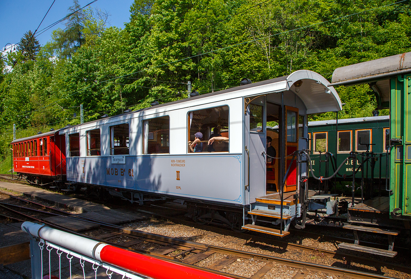 Der schmalspurige vierachsige zweite Klasse Personenwagen mit zwei Plattformen MOB B⁴ 61 seit 2016 als Geschenk von der Modellbahngruppe Obersimmental-Saanenland (MOS) bei der Museumsbahn Blonay–Chamby hier am 27 Mai 2023 im Zugverband im Museum Chaulin.

Der Wagen wurde 1906 SIG (Schweizerische Industriegesellschaft) in Neuhausen am Rheinfall als B⁴ 61 für die MOB (Montreux-Berner Oberland-Bahn) gebaut. 

Die beiden Wagen B⁴ 61 und B⁴ 62, die keine Toilette aufwiesen, wurden zusammen mit den Personenwagen BC⁴  23–26 beschafft. Grund war die Aufnahme des durchgehenden Betriebs auf der Strecke Montreux–Zweisimmen im Jahr 1905. Zudem wurden die Prognosen zur Zahl der Reisenden übertroffen. Nachdem die MOB anfänglich für die Reisezüge Drehgestell-Wagen beschafft hatte, folgten aus Kostengründen Zweiachser. Infolge von Reklamationen wechselte die MOB wiederum auf Drehgestell-Wagen, wobei es dann auch blieb.

Geschichte:
Ab 1901 in mehreren Etappen in Betrieb genommen, erreichte die Linie der Montreux-Berner Oberland (MOB) 1905 Zweisimmen. Neben der Erschließung durchquerte sie auch die bis dahin schwer zugänglichen Gebiete, insbesondere das kleine Dorf Gstaad. Das landwirtschaftliche Dorf verwandelt sich schnell in einen weltberühmten Bergkurort, es ermöglicht Touristen, die an der Waadtländer Riviera (der östlichen Teil des Nordufers des Genfersees) übernachten, direkt nach Spiez und dann nach Interlaken zu gelangen, ohne den Umweg über Bern zu machen, und gleichzeitig einen Ausflug inmitten außergewöhnlicher Panoramen zu genießen. Zudem war es damals wohl die schneller Strecke nach Spiez.

Zu diesem Zweck verband 1910 eine Expressverbindung mit Anschluss Zweisimmen Montreux in nur 4 Stunden über eine Strecke von 114 km mit Interlaken. Dieser als „Montreux-Simmenthal-Express“ bezeichnete Zug fuhr mit einem Speisewagen sowie mit Wagen der 1. Wagenklasse, was damals auf einer Nebenbahn sehr selten war. Insgesamt war das Rollmaterial von Anfang an mit einem hohen Maß an Komfort ausgestattet, wie der „B 61“, mit 30 Sitzplätzen (Polstersessel) in der 2. Klasse. Wie damals üblich war in allen Zügen auch eine dritte Klasse mit Holzbänken vorhanden; 1956 wurde das System auf europäischer Ebene mit 2 Klassen vereinheitlicht. Die bequemen historischen Polstersessel wurden dann 1956 durch Holzbänke ersetzt, dadurch hatte der Wagen nun 40 Sitzplätzen in der „neuen“ 2. Klasse. Der „B 61“ beendete seine „aktive“ Karriere bei der MOB Ende der 1979 im Regionalverkehr, insbesondere zwischen Montreux und Les Avants. Er wurde 1979 für 100 Franken an die MOS - Modellbahngruppe Obersimmental-Saanenland (MOS) verkauft. Die MOS nutzte ihn von 1979 bis 2015 als Vereinslokal in Saanen, zusammen mit dem 1995 übernommenen ursprünglichen MOB BFZe 4/4 26 und K 529. 2015 musste die Modellbahngruppe (heute aufgelöst) den Standort in Saanen infolge Sanierung der Bahnstrecke und des Bahnhofes aufgeben und verlegte diesen nach Zweisimmen. Sie schenkte in der Folge 2016 den Wagen B⁴ 61 (ohne Inneneinrichtung) der Museumsbahn Blonay–Chamby. Bei der BC wurde er komplett überholt und in den Originalzustand, einschließlich der bequemen historischen Polstersessel, versetzt. Am 10. Mai 2018, anlässlich des „Mega Steam Festival“ dem 50-jährigenJubiläums der BC wurde er in Dienst gestellt und präsentiert. 
TECHNISCHE DATEN:
Hersteller: SIG (1906) 
Spurweite: 1.000 mm (Meterspur)
Achsanzahl: 4 (in 2 Drehgestellen)
Länge über Puffer: 11.630 mm 
Länge Wagenkaten: 10.630
Höhe / Breite: 3.600 mm / 2.700 mm
Drehzapfenabstand: 6.500 mm 
Achsabstand im Drehgestellt: 1.200 mm
Drehgestelle Typ: SIG, einfache Federung
Laufraddurchmesser: 750 mm (neu)
Eigengewicht: 9.800 kg
Sitzplätze: 30 (40 mit Holzbänken von 1956 bis 1979)
Höchstgeschwindigkeit: 50 km/h
Kupplungen: Mittelpuffer mit einer Schraubenkupplungen (Zp 1)

Quellen: Museumsbahn BC, x-rail.ch und wikipedia
