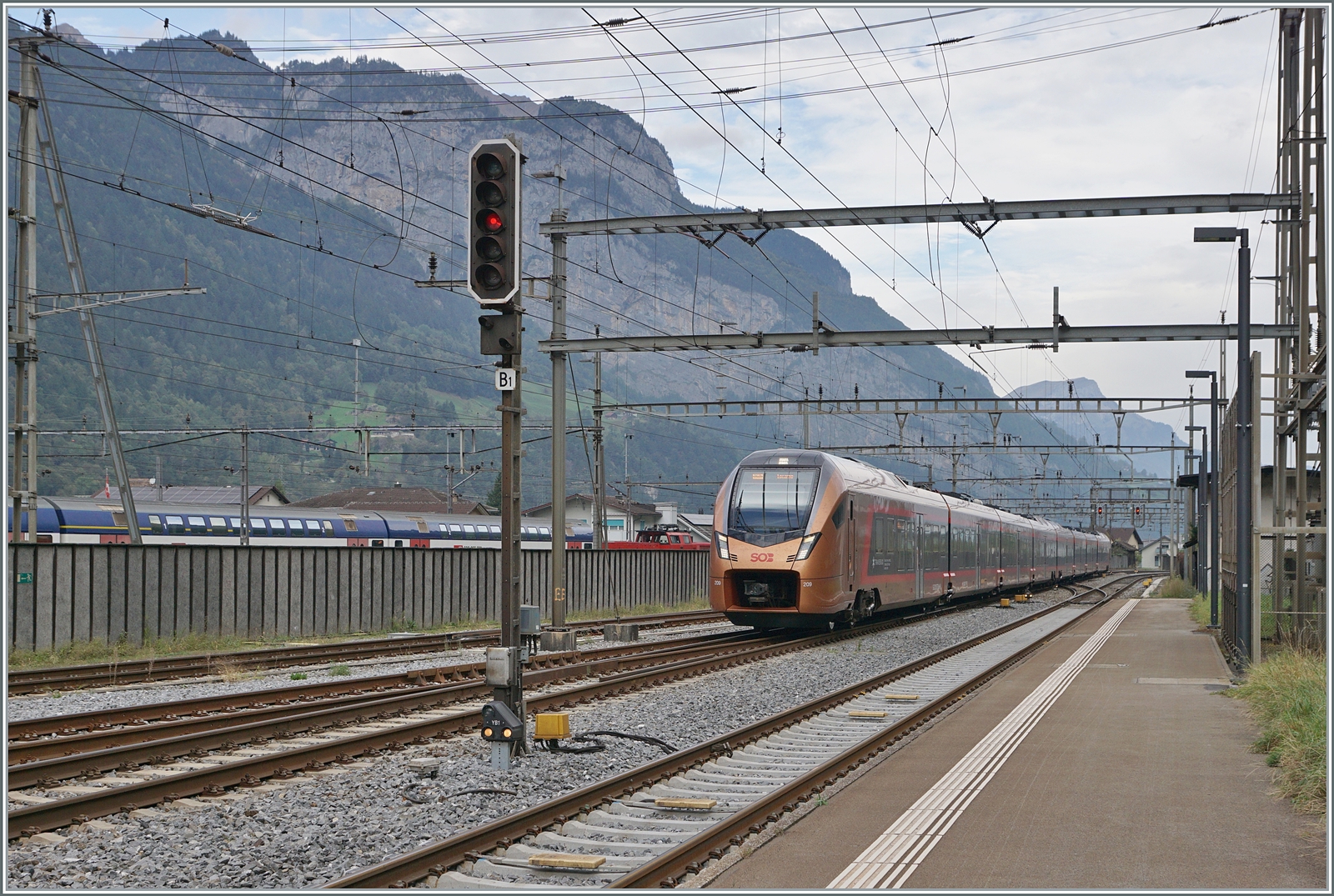 Der SOB  Traverso  RABe 526 209 als  Treno Gotthardo  von Basel nach Locarno erreicht Erstfeld. Im Hintergrund, hinter einer (unnützen) Lärmschutzwand rangieren SBB Aem 940 Züricher S-Bahn Doppelstock Wagen.

19. Oktober 2023