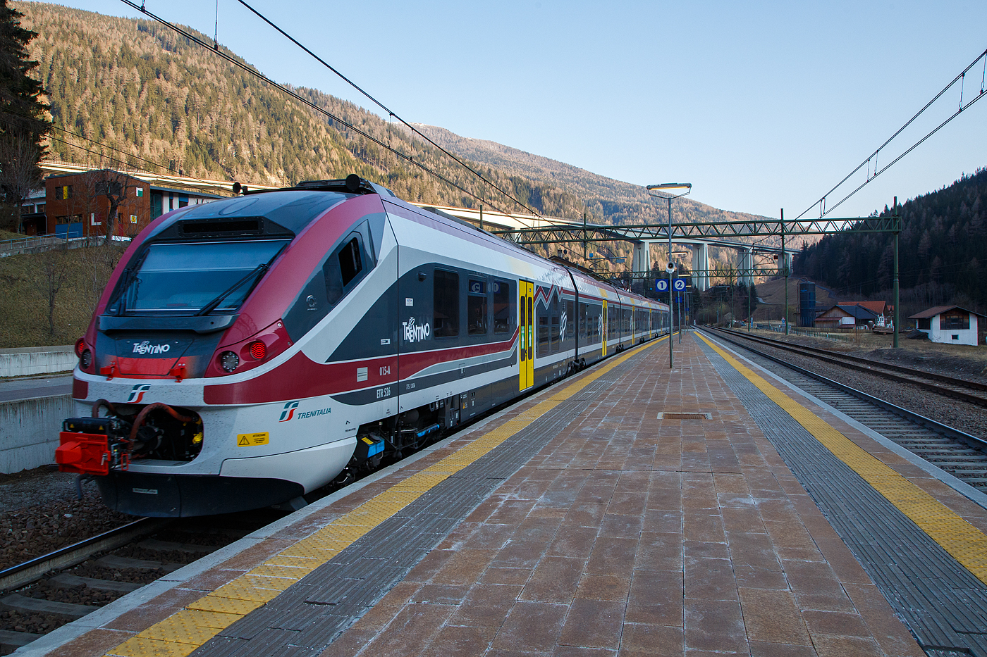 Der Trenitalia Trentino ETR 526 015, ein sechsteiliger Alstom Coradia Meridian „JAZZ“ hat am späten Nachmittag des 27 März 2022, als Regionalzug (R 17249) vom Brenner/Brennero via Bozen/Bolzano nach Meran/Merano, den Bahnhof Gossensaß/Colle Isarco erreicht. Im Hintergrund das Gossensaß-Viadukt (Viadotto Colle Isarco) der Brennerautobahn (Autostrada del Brennero / Autostrada A22).