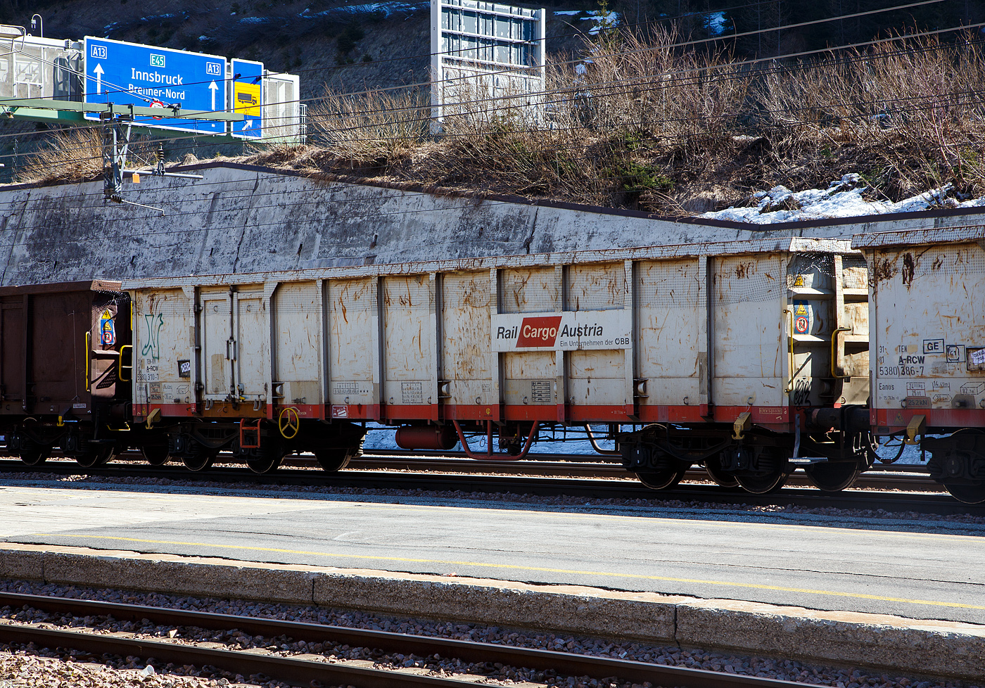 Der vierachsige Drehgestell-Hochbordwagen 31 81 5380 310-4 A-RCW der Gattung Eanos der Rail Cargo Austria (zur �BB) am 28 M�rz 2022 im Bahnhof Brenner /Brennero.

Der Wagen besitzt je Seite eine nur kleine zweifl�gelige T�re 1.800 x 1.800 mm), die eigentlich lediglich der Begehung dient, da die Wagen fast ausschlie�lich durch Kippen oder mittels Krane (Magnet oder Greifer) entladen werden. Er dient vorzugsweise dem Transport von witterungsunempfindlichen Sch�tt- und St�ckg�tern (wie Kohle, Briketts, Schrott, Erze, Steine und Erden). Das Untergestell ist eine Schwei�konstruktion aus Walzprofilen in den Materialg�ten St 37 und St 52 und ist Rahmenbauweise ausgef�hrt. Der Fu�boden besteht aus 6 mm dicken Blechen. Der G�terwagen ist f�r die Entladung �ber eine Seitenkippanlage geeignet.

TECHNISCHE DATEN:
Spurweite: 1.435 mm (Normalspur)
Achsanzahl: 4 in zwei Drehgestellen
L�nge �ber Puffer: 15.740 mm
Drehzapfenabstand: 10.700 mm
Achsabstand im Drehgestell: 1.800 mm
Laufraddurchmesser: 920 mm
Ladel�nge: 14.490 mm
Ladefl�che: 39,4 m�
Laderaum:  82,7 m�
H�chstgeschwindigkeit: 100 km/h (beladen) / 120 km/h (leer)
Max . Ladegewicht: 58,0 t ab Streckenklasse C, 66,0 t  ab Streckenklasse D
Eigengewicht: 24.000 kg
Kleinster bef. Gleisbogenradius: R 35 m
Bremse: KE-GR-A (K)
Bremssohle: Jurid C 810
Handbremse: Ja
Intern. Verwendungsf�higkeit: TEN-GE
