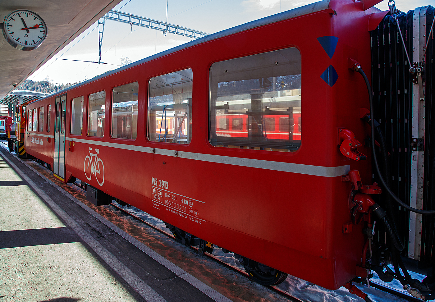 Der vierachsige Velowagen (Fahrradtransportwagen) RhB WS 3913, ex RhB B 2339 am 20 Februar 2017 im RhB Bahnhof St. Moritz.

Der Wagen wurde 1956 von SIG (Schweizerische Industrie-Gesellschaft) in Neuhausen am Rheinfall gebaut. Diese Wagenserie von 13 Stück SIG-Leichtstahlwagen mit Mitteleinstieg (AB⁴ü 1513-1518 und die B⁴ü 2334–2340) wurde, kurz nach Abschaffung der dritten Klasse, von 1956 bis1957, an die RhB geliefert. Diesmal kamen die Wagen aber von SIG Neuhausen (und nicht von SWS) und wiesen viele Gemeinsamkeiten mit den Leichtmetallwagen gleicher Provenienz auf: Flügeltüren, WC beim Mitteleinstieg, Stirnwandtüren direkt im Personenabteil, gleicher Sitzteiler. Die Wagen waren aber 18,22 m lang, liefen auf SIG-Torsionsstab-Drehgestellen (System Frei) und wiesen von Anfang an eine leichte Polsterung in der 2. Klasse auf. Je drei Wagen erhielten zusätzlich Gleichstromheizung für den Einsatz nach Arosa. Zwei Wagen (1517–1518) hatten eine Zeit lang ein Bremszahnrad für den Einsatz bis Brig. 

Zwischen 1989 und 1991 baute die RhB die 1956 in Dienst gestellten Mitteleinstiegswagen AB 1514-1518 und B 2337-2340 zu Pendelzugwagen um und bediente damit hauptsächlich die Strecken Davos-Filisur sowie Samedan-Pontresina im Oberengadin. Sie erhielten anstelle der beiden zweiflügeligen Falttüren moderne Schwenkschiebetüren.

Ab 2000 baute die RhB einige dieser Wagen (dieser 2003) zu Velowagen um. Im Gebiet Engadin wird der Velosport durch die Tourismus-Organisationen sehr stark gefördert. Dies hat auch zur Folge, dass der Velotransport per Bahn zugenommen hat. Der bestehende Stauraum im Gepäckabteil hat oft nicht mehr genügt.

TECHNISCHE DATEN:
Baujahr und Hersteller: 1956 - SIG
Spurweite: 1.000 mm
Anzahl der Achsen: 4
Länge über Puffer: 18.220 mm
Drehgestellbauart: SIG Torsionsstab
Sitzplätze: 56
Eigengewicht: 17,0 t
zulässige Geschwindigkeit: 90 km/h
Lauffähig: StN (Stammnetz) / MGB (Matterhorn Gotthard Bahn)