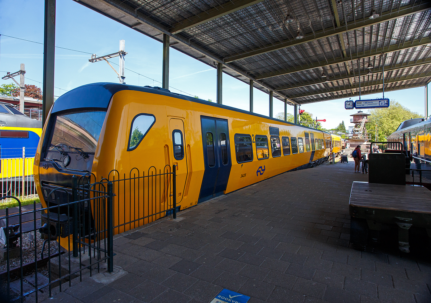 Der zweiteilige Dieseltriebwagen NS 3426 „Buffel“, deutsch Büffel, NL-NS 95 84 5131426-6, (Bk 3426 + ABk 3426), der NS Baureihe/Serie DM '90 (Dieselmaterieel '90), am 29 April 2025 im Het Spoorwegmuseum (bis 2005 NSM - Nederlands Spoorwegmuseum / Niederländischen Eisenbahnmuseum) in Utrecht im Bahnhof Maliebaanstation. Ein sehr schönes Eisenbahnmuseum das zum Verweilen einlädt, leider fehlte uns dieses Mal die Zeit dafür. 

Der diesel-hydraulische Triebzug wurde 1998 von der Waggonfabrik Talbot GmbH & Co. (heute Bombardier) in Aachen (D) für die NS - Nederlandse Spoorwegen N.V. (Niederländische Eisenbahnen AG) gebaut und geliefert. Die komplette elektrische Ausrüstung, sowie die Zugsteuerungs- und Diagnosefunktionen, durch Holec in Ridderkerk (NL), heute Alstom. Die Innenausstattung wurde von DUEWAG (Düsseldorfer Waggonfabrik) in Krefeld (D), heute Siemens, gefertigt und von dort aus wurden die Züge auch in die Niederlande transportiert. Der Büffel bzw. Triebzug 3426 ging 2017 außer Betrieb und wurde Anfang 2018 an das Eisenbahnmuseum übergeben.

Dieselmaterieel '90 (DM '90):
Die zweiteiligen Dieseltriebwagen der NS-Serie Dieselmaterieel '90 (DM '90), offiziell Buffel (Büffel) genannt, da die Frontform an einen Büffelkopf erinnert, war eine Serie aus 53 zweiteiligen Dieseltriebwagen die von Waggonfabrik Talbot in Aachen gebaut wurden. Die Triebzüge basieren teilweise auf dem Stoptrein-Material '90, dem „Railhopper“. Die Buffels wurden ab 1996 von der Niederländischen Eisenbahn und ab 1999 von Syntus eingesetzt. Die letzten Züge der Niederländischen Eisenbahn waren bis 2017 im Einsatz.

Die Büffel waren auf nichtelektrisierten Regionalbahnstrecken der NS in den Niederlanden im Einsatz. Heute verkehren auf diesen Bahnstrecken andere private Eisenbahngesellschaften (wie u.a. Syntus, Arriva und Connexxion) und nicht die NS. So braucht die NS keine Dieselzüge mehr und verabschiedete sich vom Büffel.

Ausstattung und Technik:
Wie der elektrische Triebzug Stoptreinmaterieel '90 (auch von Talbot gebaut), der die Grundlage für den Büffel bildete, weist der DM'90 eine etwas andere gestaltete maximale Breite von 3,20 Metern auf. Durch seine geschickte Gestaltung der Wagenkästen mit gekrümmten Seitenwänden) und die Begrenzung des seitlichen Federwegs ist es möglich, das Wagenprofil 30 Zentimeter breiter als bei den meisten Zügen zu machen und dabei immer noch das Standardprofil einzuhalten. Durch diese Breit wäre es möglich gewesen, in der zweiten Klasse fünf Sitzplätze nebeneinander zu schaffen, was jedoch nicht umgesetzt wurde. Angetrieben wird DM'90 von zwei 6-Zylinder-Reihen-Dieselmotoren von Cummins (Typ NTA 855 R4) mit einer maximalen Leistung von jeweils 320 kW. Das Getriebe von Voith (Typ T211 rzze) ist hydrodynamisch (Voith, Typ T211 rzze). Der DM'90 hat eine Höchstgeschwindigkeit von 140 km/h. Der Büffel konnte in Mehrfachtraktion mit der älteren (ebenfalls dieselhydraulischen) Wadloper (DH1 und DH2) fahren, allerdings war die Höchstgeschwindigkeit dann auf die des Wadlopers von 100 km/h begrenzt. Der Büffel bot 135 Passagieren Sitzplätze (123 in der zweiten Klasse und 12 in ersten Klasse). Als Drehgestelle dienten die Typen RMO 9000 (von Stork RMO Werkspoor), die auch für die doppelstöckigen Interregio-Züge verwendet wurden. Ursprünglich sollten die DM‘90 den gleichen Kopf wie SM‘90 haben, auf Anraten der Marketing- und Designabteilung wurde jedoch der stromlinienförmige Kopf verwendet, der eigentlich schon für SM‘90 entwickelt worden war und Reisende stärker ansprechen sollte.

Die Kombination aus Scheibenbremsen und der ruhige Lauf führte zu einer schlechten Erkennung der Ausrüstung. Auf den Strecken, auf denen die DM'90 verkehrte, installierte der Bahnbetreiber häufig Achszähler. 

TECHNISCHE DATEN:
Serie: NS 3400 - DM '90 (Dieselmaterieel '90) „Buffel“
Gebaute Anzahl: 53
Nummerierung: 3401-3453
Typ: diesel-hydraulischer Triebzug
Baujahre: 1996 bis 1998
Ausmusterung: 2017
Hersteller: Waggonfabrik Talbot GmbH & Co. in Aachen (D), heute Bombardier
Zulieferung elektrische Ausrüstung: Holec in Ridderkerk (NL), heute Alstom
Zulieferung Innenausstattung: DUEWAG in Krefeld (D), heute Siemens
Spurweite: 1.435 mm (Normalspur)
Achsfolge: 2'B' + B'2' (8 Achsen in 4 Drehgestellen)
Zusammensetzung: Bk + ABk

Länge über Kupplung: 52.340 mm
Breite: 3.200 mm
Höhe: 4.142 mm
Treib- und Laufraddurchmesser: 920 mm (neu) / 840 mm (abgenutzt)
Achsabstand im Triebdrehgestell: 2.750 mm
Achsabstand im Laufraddrehgestell: 2.600 mm
Motoren: 2 Stück Cummins 6-Zylinder-Reihen-Dieselmotoren vom Typ NTA 855 R4
Motorleistung: 2 x 340 KW = 640 kW (870 PS)
Getriebe: 2 Stück hydrodynamisches Turbogetriebe von Voith vom Typ T211 rzze
Höchstgeschwindigkeit: 140 km/h
Beschleunigung: 0,6 m/s²
Bremsverzögerung: 1,2 m/s² 
Eigengewicht: 95,2 t 
Fußbodenhöhe: 1.160 mm 
Anzahl der Doppeltüren je Seite: 4 [zweiteilige Pneumatische Pendeltüren 1.300 mm breit]
Sitzplätze (gesamt): 135
Sitzplätze in der 1. Klasse: 12
Sitzplätze in der 2. Klasse: 123
Anzahl der Klappsitze: 34
Stehplätze (4 Pers./m²): 156
Tankvolumen: 2 x 1.000 = 2.000 Liter
Kupplung: Scharfenberg

Verkäufe:
32 Triebzüge wurden 2020 an die SKPL - Stowarzyszenie Kolejowych Przewozów Lokalnych (Vereinigung von Lokalbahnbetrieben) nach Polen verkauft, wo sie nach Modifizierungen seit 2024 als SD85 im Einsatz sind. 

14 Triebzüge wurden 2021 an die Firma Brouwer in Blerick (bei Venlo) verkauft, die diese konnte sie an die rumänische Betreiber Ferotrans-TFI verkaufen.

1 Triebzug (3452) wurde im Januar 2021 an die HTFSE Happy Train Fleet Services B.V. verkauft. Dieser Zug soll zukünftig wieder fahrbereit gemacht werden.

Von den 53 Zuggarnituren wurden letztlich 47 verkauft. 
5 Triebzüge (3403, 3405, 3409, 3410 und 3424) wurden aus unterschiedlichen Gründen verschrottet. 
Der Triebzug 3426 wurde an das Eisenbahnmuseum übergeben.
