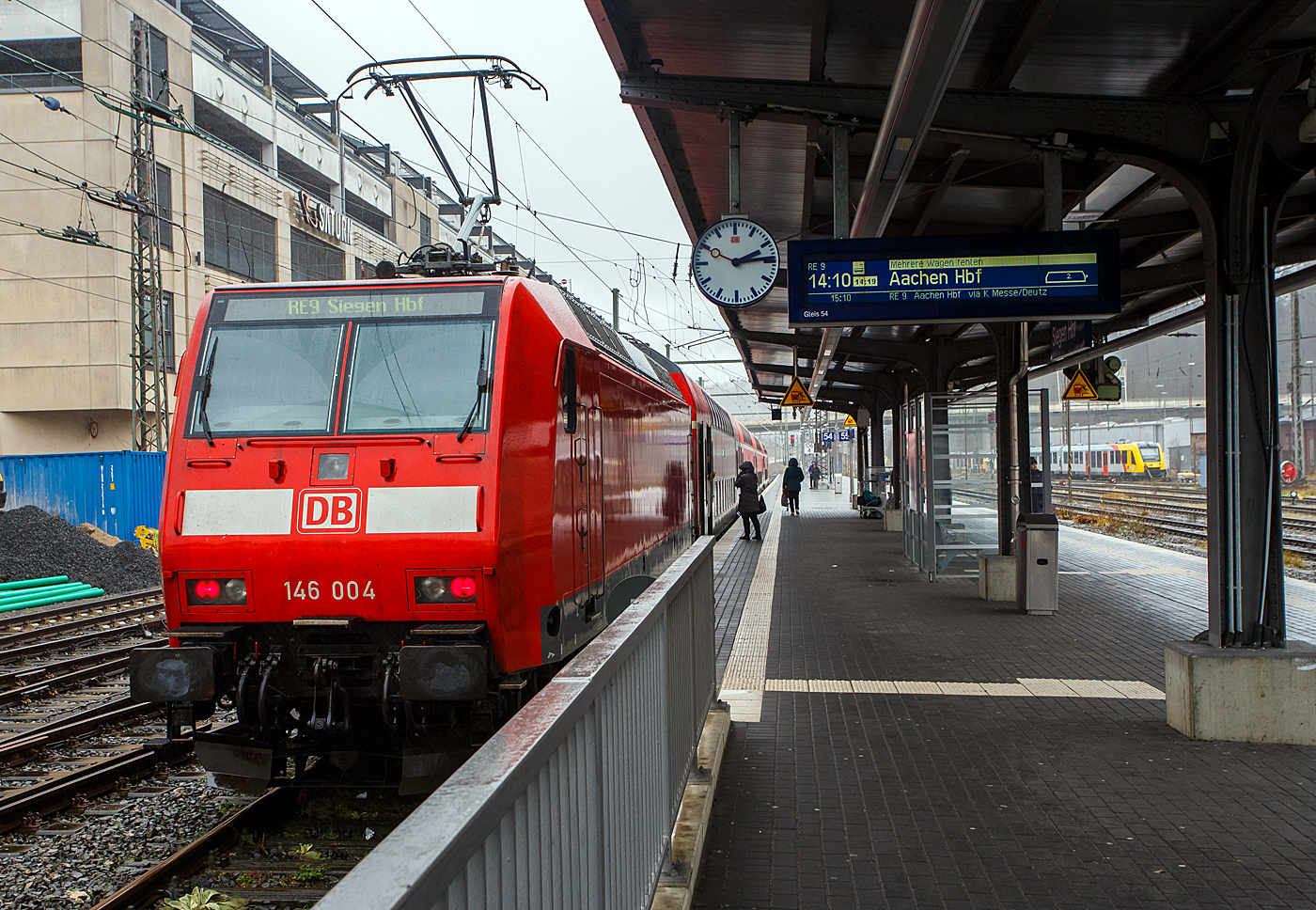 Die 146 004-7 (91 80 6146 004-7 D-DB) der DB Regio NRW steht am 29 Dezember 2023 auf Gleis 54 im Hauptbahnhof Siegen Steuerwagen voraus mit dem RE 9 rsx - Rhein-Sieg-Express (Siegen– Köln - Aachen) zur Abfahrt breit. 

Die Bahnsteiguhr zeigte 14:14, laut Anzeigentafel war die Abfahrt auf 14:19 Uhr verschoben (da der Zug gerade den Hbf erreicht hatte). So dachte ich mach erst noch ein Bild und dann steigen wir ein. Foto gemacht, zur Wagentür gegangen, aber die Tür geht nicht mehr auf, sondern der Zug fährt ohne uns ab. Da war die DB doch mal etwas schneller;-)
