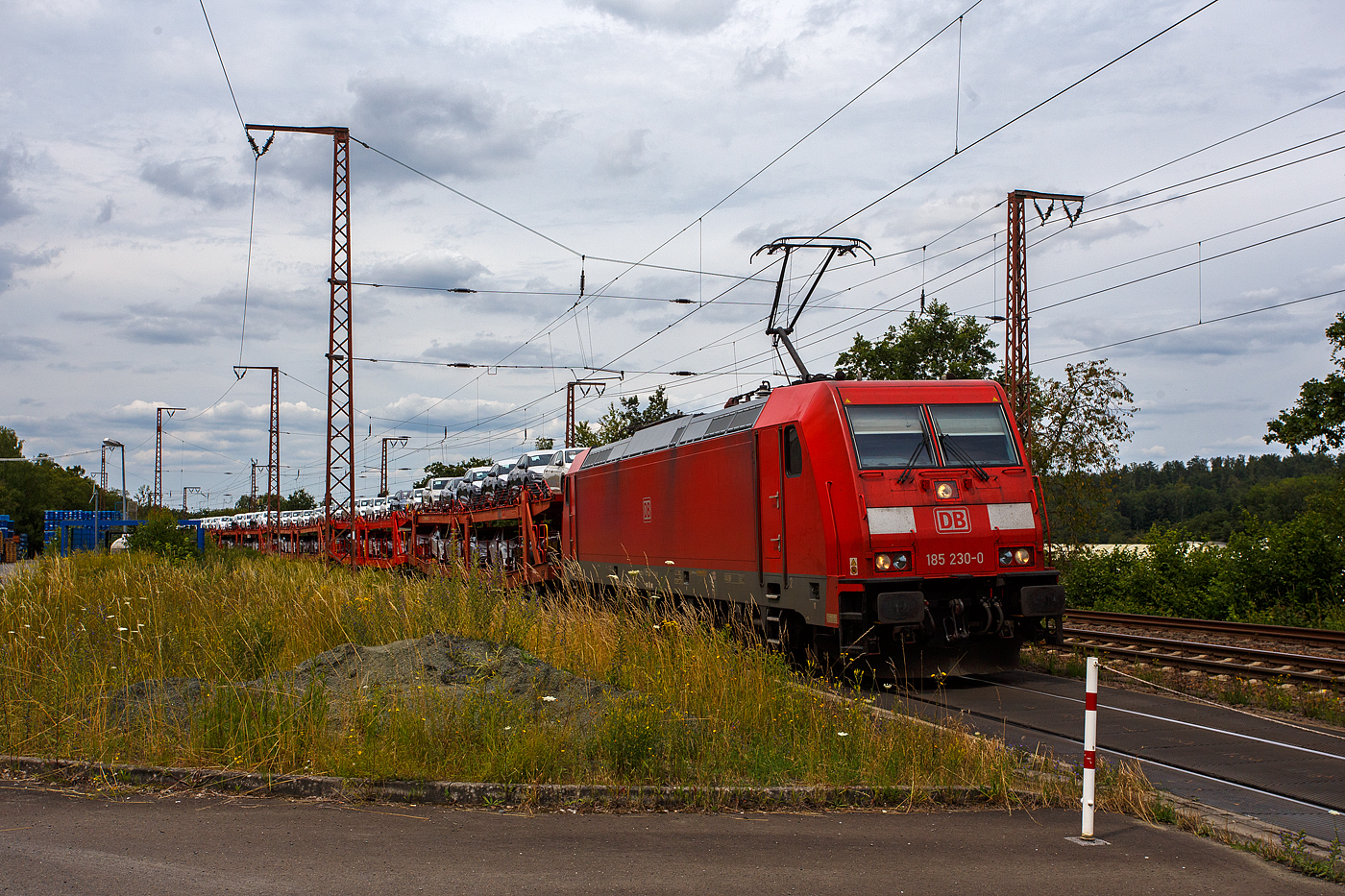 Die 185 230-0 (91 80 6185 230-0 D-DB) der DB Cargo AG fährt am 19 Juli 2024, mit einem mit PKW´s aus der „Stadt des KdF-Wagens bei Fallersleben“ (ab 1945 Wolfsburg) beladen Autotransportzug (Wagen der Gattung Laaers 560 der DB Cargo Logistics GmbH, ex ATG), durch Rudersdorf (Kreis Siegen) in Richtung Süden (Frankfurt/Main).

Die TRAXX F140 AC 2 wurde 2005 bei Bombardier in Kassel unter der Fabriknummer 33757 gebaut.  