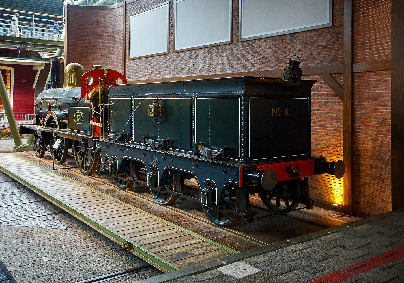Die 1865 gebaute 1B Dampflokomotive SS 13 „de Bril“ (die Brille), ab 1921 NS 705 (NS-Baureihe 700), am 24 Juni 2025 im Het Spoorwegmuseum (bis 2005 NSM - Nederlands Spoorwegmuseum / Niederländischen Eisenbahnmuseum) in Utrecht im Bahnhof Maliebaan. Ein sehr schönes Eisenbahnmuseum das zum Verweilen einlädt. Übrigens Het vor Spoorwegmuseum heißt einfach „Das“, so heißt übersetzt das Museum einfach „Das Eisenbahnmuseum“.

Die Dampflok wurde 1865 von Beyer Peacock & Co. Ltd. in Manchester (GB) unter der Fabriknummer 533 gebaut und an die damalige SS - Maatschappij tot Exploitatie van Staatsspoorwegen (deutsch: Gesellschaft zum Betrieb von Staatseisenbahnen) geliefert. Ab 1921, nach der Zusammenlegung des Rollmaterials der SS und der NRS, wurde die Lok zur NS 705. Die Lokomotive SS 13 (NS 705) wurde 1932 im Alter von 67 Jahren ausgemustert und vor dem Eisenbahnmuseum abgestellt. Es handelt sich um die älteste noch erhaltene Dampflokomotive der Niederlande. Sie ist (im Jahr 2025) 160 Jahre alt! Der dreiachsige Tender stammt von der SS 8 und wurde 1863 gebaut. Die Lokomotive SS 8 (deren Tender heute zur SS 13 gehört) wurde 1868 durch eine Kesselexplosion in Harlingen schwer beschädigt, woraufhin der (unbeschädigte) Tender zur SS 13 kam. Der Tender trägt übrigens noch immer seine ursprüngliche Nummer SS 8 auf der Rückseite. Ursprünglich hatte diese Lokomotive einen zweiachsigen Tender. Ende des Zweiten Weltkriegs wurde sie von den zurückweichenden Deutschen Truppen in Maastricht (wo sich damals das EM befand) schwer beschädigt. Im Jahr 1951 wurde sie schließlich von der Hauptwerkstatt in Tilburg in ihren Originalzustand zurückversetzt und anschließend ins Eisenbahnmuseum gebracht. Die Lokomotive erhielt im Jahr 2000 mit einem neuen Kessel, ist aber nicht betriebsbereit.

Die NS 700-Serie war eine Serie von 75 Dampflokomotiven der Niederländischen Eisenbahnen (NS), die zwischen 1865 bis 1873, an ihre Vorgängergesellschaften, Maatschappij tot Exploitatie van Staatsspoorwegen (SS, „Gesellschaft zum Betrieb von Staatseisenbahnen“) und der Noord-Brabantsch-Duitsche Spoorweg-Maatschappij (NBDS „Nord-Brabantisch-Deutsche Eisenbahngesellschaft“) geliefert wurden. 

Für den Betrieb der neuen Eisenbahnstrecken Arnheim – Deventer, Zutphen – Glanerbrug, Maastricht – Venlo und Almelo – Hengelo im Jahr 1865 benötigte die SS neue Lokomotiven. Eine große Anzahl von Lokomotiven auf Basis der SS 5-8 wurden bei den Werken von Beyer, Peacock and Company in Manchester bestellt und zwischen 1865 und 1869 als SS 9-16 und SS 21-78 ausgeliefert. Die Maschinen waren damals die leistungsstärksten und schnellsten Lokomotiven auf den niederländischen Eisenbahnen. Die übersprungenen Nummern SS 17–20 wurden durch die 1865 gelieferten Güterzugdampflokomotiven (spätere Baureihe NS 2900) übernommen. Kessel und Zylinder waren die gleichen wie bei der SS 5-8-Serie. Die Antriebsräder waren kleiner und der maximale Dampfdruck wurde auf 8,3 kg/cm² erhöht, was die Zugkraft erhöhte. Die SS 9-16 wurden mit einem zweiachsigen Tender ausgeliefert, andere Lokomotiven waren mit einem dreiachsigen Tender ausgestattet. Im Jahr 1884 wurde bei vier Lokomotiven der Baureihe SS 9–16 der zweiachsige Tender gegen einen dreiachsigen Tender der eingestellten Baureihe SS 5–8 ausgetauscht. Anfangs waren die Lokomotiven nicht mit einem Lokführerstand ausgestattet. Heizer und Lokführer waren vor Witterungseinflüssen lediglich durch eine Schutzbrille (der Brillenplatte), einer Stahlplatte mit 2 runden Fenstern über der Feuertür geschützt. Dieser Brillenplatten verdankt die Lok auch ihren Spitznamen „De Bril“ „Die Brille“. Diese Brillenplatten sorgte nur für etwas Schutz vor dem Fahrtwind und Witterungseinflüssen für den Lokführer und Heizer, deren Arbeitsplatz ist mit Absicht nicht allzu bequem. Die SS befürchtet, dass die Männer während der Fahrt einschlafen könnten. In den 1880er Jahren wurde die Serie mit dem Bremssystem von Westinghouse ausgestattet, außerdem erhielten sie ein Dach über dem Führerstand, später sogar einem geschlossenen Führerstand.

Bedingt durch den Ersten Weltkrieg wurde 1917 eine Zweckgemeinschaft der unabhängigen Eisenbahngesellschaften HSM (Hollandsche IJzeren Spoorweg-Maatschappij) und SS (Maatschappij tot Exploitatie van Staatsspoorwegen) gegründet. Die beiden Gesellschaften errichteten einen gemeinsamen Bahnbetrieb, blieben aber rechtlich unabhängig. Dies änderte sich 1938, als HIJSM und SS vollständig fusionierten und in der AG NS (Nederlandse Spoorwegen, früher Nederlandsche Spoorwegen geschrieben) aufgingen. Das Rollmaterial wurde bereits 1921 zusammengelegt, so wurden die Lok zur NS 705 nummeriert.

TECHNISCHE DATEN:
NS-Serie: 700
Hersteller: Beyer Peacock & Co. Ltd. in Manchester (GB)
Gebaute Anzahl: 75
Typ: Schnellzuglokomotive
Spurweite: 1.435 mm (Normalspur)
Achsfolge: 	1 B (engl. 2-4-0), gekuppelt mit dreiachsigem Tender
Länge über Puffer: 13.637 mm 
Treibraddurchmesser: 1.700 mm (neu) 
Laufraddurchmesser (Lok und Tender): 1.067 mm (neu)
Gewicht: 49,3 t (28,8 t Lok und 20,5 t Tender)
Höchstgeschwindigkeit: 80 km/h
Rostfläche: 1,38 m²
Gesamtheizfläche: 80 m²
Kesselüberdruck: 8,3 kg/cm² 
Anzahl der Zylinder: 2 (Ø 406 mm x 508 mm Hub)
Steuerung: Allan
Anhängelast: 2.864 kg
Wasservorrat: 6,6 m³ 
Kohlevorrat: 3,5 t

Quellen: Somda RailWiki.nl, Het Spoorwegmuseum, nmld.nl, Wikipedia (NL)
Stand/Überarbeitung: Oktober 2025
