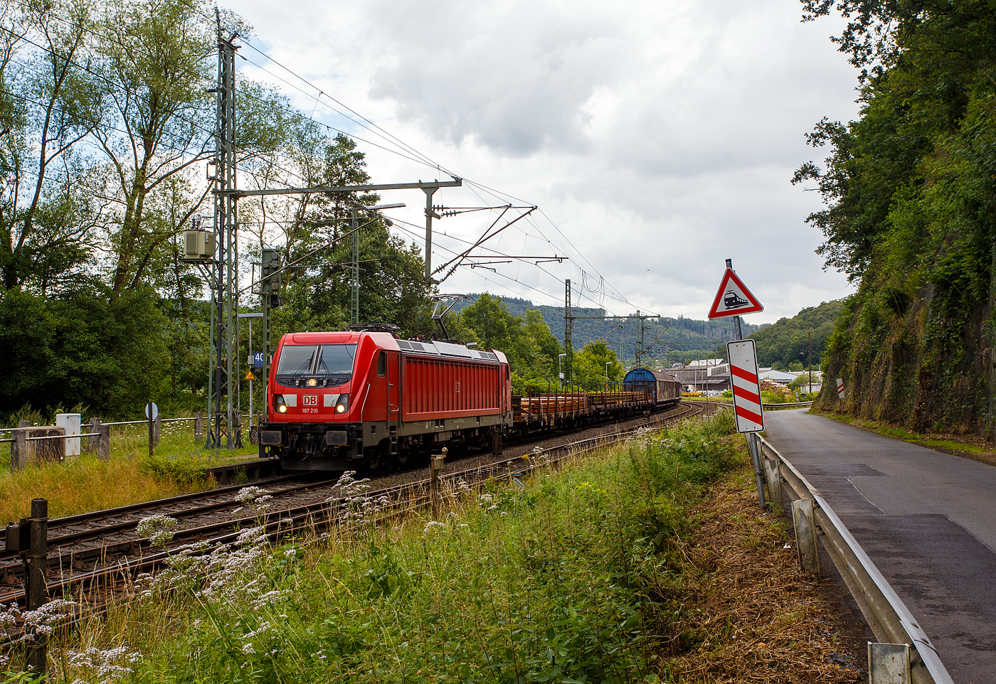 Die 187 210-0 (91 80 6187 210-0 D-DB) der DB Cargo AG fährt am 10 Juli 2024 mit einem langen gemischten Güterzug durch Scheuerfeld (Sieg) in Richtung Köln.

Die Bombardier TRAXX F140 AC3 wurde 2021 von der Bombardier Transportation GmbH in Kassel unter der Fabriknummer 	KAS 35746 gebaut. Die TRAXX F140 AC3 Varianten der DB Cargo (BR 187.1) haben keine Last-Mile-Einrichtung. Die Höchstgeschwindigkeit beträgt 140km/h. Die Lok hat nur die Zulassung für Deutschland. Die Lokomotiven können in gemischter Mehrfachtraktion mit BR185 und BR186 eingesetzt werden.
