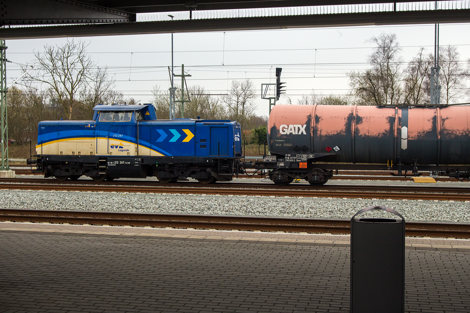 Die 212 247-1 (92 80 1212 247-1 D-EVB) der EVB - Eisenbahnen und Verkehrsbetriebe Elbe-Weser GmbH steht am 11 März 2024 mit einem Kesselwagenzug im Bahnhof Sande (Friesland).

Die Streckendiesellokomotive wurde 1965 von der MaK - Maschinenbau Kiel GmbH (Kiel) unter der Fabriknummer 1000294 gebaut und als V 100 2247 an die DB - Deutsche Bundesbahn ausgeliefert. Zum 01.01.1968 erfolgte die Umzeichnung in DB 212 247-1, so fuhr sie bis zur Ausmusterung 2002. Über die ALS - ALSTOM Lokomotiven Service GmbH in Stendal  ging sie 2004 an die MWB - Mittelweserbahn GmbH in Bruchhausen-Vilsen als MWB V 1251 (92 80 1212 247-1 D-MWB. Seit 2015 ist sie nun bei der evb. 

Die Eisenbahnen und Verkehrsbetriebe Elbe-Weser GmbH (evb) ist ein Verkehrsunternehmen im als Elbe-Weser-Dreieck bekannten Teil Niedersachsens mit Sitz in Zeven (bzw. Bremervörde). Eigentümer sind zu 59 % die Hannoversche Beteiligungsgesellschaft Niedersachsen, 24 % Land Niedersachsen, sowie 17 % Landkreise und Gemeinden aus der Elbe-Weser-Region.
