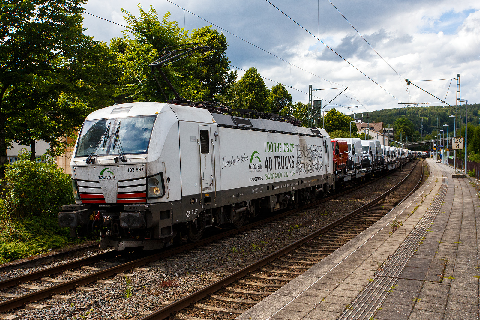 Die „wei�e“ an die TX Logistik AG (Bad Honnef) vermietete SIEMENS Vectron MS 193 597  I do the Job of 40 Trucks  (91 80 6193 597-2 D-ATLU) der Alpha Trains Luxembourg s.�.r.l. (Luxembourg) f�hrt am 14 Juli 2024, mit einem langen mit Nutzfahrzeuge (FIAT - Kastenwagen) beladenen Flachwagenzug (2 x 2 achsige Flachwageneinheiten), durch Kirchen (Sieg) in Richtung K�ln.

Nochmals einen lieben Gru� an den netten Lokf�hrer zur�ck.

Die Siemens Vectron MS wurde 2020 von Siemens Mobility GmbH in M�nchen-Allach unter der Fabriknummer 22865 gebaut und war erst als 91 80 6193 597-2 D-SIEAG der Siemens Mobility GmbH zugelassen. Im Jahr 2021 wurde sie an die Alpha Trains Belgium NV/SA in Antwerpen verkauft und ab Juni 2021 an die TX Logistik AG vermietet. 

Diese Vectron Lokomotive ist als MS – Lokomotive (Mehrsystemlok) mit 6.400 kW Leistung und 160 km/h H�chstgeschwindigkeit konzipiert. Hier in der Version A39 hat sie die Zulassungen f�r Deutschland, �sterreich, Schweiz, Italien, Niederlande und Belgien (D/A/CH/I/NL/B).Die SIEMENS Vectron MS der Version A 39 besitzt die Zugsicherungssysteme ETCS BaseLine 3, sowie
f�r Deutschland (PZB90 / LZB80 (CIR-ELKE I)), 
f�r �sterreich (ETCS Level 1 mit Euroloop, ETCS Level 2, PZB90 / LZB80),
f�r die Schweiz (ETCS Level 2, ZUB262ct, INTEGRA)
f�r Italien (SCMT)
f�r die Niederlande (ETCS Level 1, ETCS Level 2, ATB-EGvV)
und f�r Belgien (ETCS L1, ETCS L2, TBL1+)

TECHNISCHE DATEN der Vectron MS A39:
Spurweite: 1.435 mm (Normalspur)
Achsformel: Bo'Bo'
L�nge �ber Puffer: 18.980 mm
Drehzapfenabstand: 9.500 mm
Achsabstand im Drehgestell: 3.000 mm
Breite: 3.012 mm
H�he: 4.248 mm
Raddurchmesser : 1.250 mm (neu) / 1.160 mm (abgenutzt)
Gewicht: 90 t
Spannungssysteme: AC 15 kV 16,7 Hz und AC 25 kV 50 Hz (Wechselstrom), sowie DC 3 kV und DC 1,5 kV (Gleichstrom)
Max. Leistung am Rad: 6.400 kW (Fahren und Netzbremse)
Leistungsfaktor: nahe 1
H�chstgeschwindigkeit: 200 km/h
Anfahrzugskraft: 320 kN (optional 350 kN)
Dauerzugkrauft: 250 kN
Elektrische Bremskraft: 150 kN (240 kN mit erh�hte E-Bremskraft)
Kraft�bertragung: Ritzelhohlwellenantrieb
Kleinster befahrbarer Bogenradius (Strecke):	R 140 m
Kleinster befahrbarer Bogenradius (Depot): R 80 m

