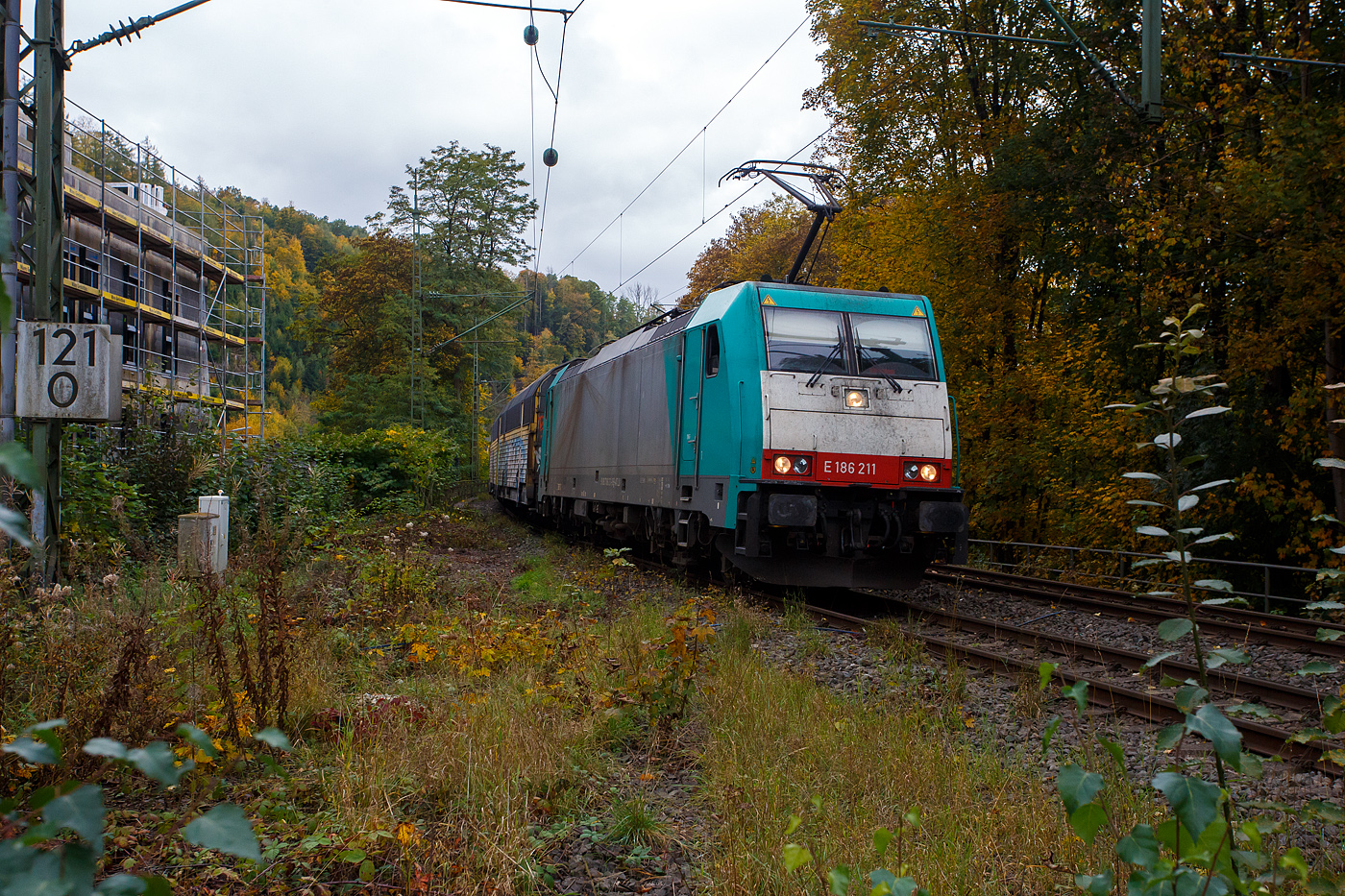 Die an die Crossrail Benelux N.V. (100% Tochterder BLS Cargo AG) vermietete E 186 220 (91 88 7186 211-9 B-ATLU) der Alpha Trains Belgium, ex COBRA 2819 (91 88 7186 211-9 B-B), fährt am 09 Oktober 2025 mit einem geschlossen Doppelstock- Autotransportzug der ARS Altmann AG (mit Wagen der Gattung Hccrrs), durch Kirchen/Sieg in Richtung Siegen.

Die Bombardier TRAXX F140 MS wurde 2008 von Bombardier Transportation in Kassel unter der Fabriknummer 34398 gebaut. Die Multisystemlokomotive hat die Zulassungen bzw. besitzt die Länderpakete für Deutschland, Österreich, die Niederlande und Belgien. (D/A/NL/B). In Deutschland, der Niederlande und in Belgien ist sie für eine Höchstgeschwindigkeit von 160 km/h zugelassen, in Österreich nur für 140 km/h.

Lebenslauf und Bezeichnungen der Lok:
•	Von 2008 bis 2010 NMBS /SNCB - Nationale Maatschappij der Belgische Spoorwegen / Société Nationale des Chemins de Fer Belges / Nationale Gesellschaft der Belgischen Eisenbahnen als 2819 (91 88 7186 211-9 B-B) bzw. Cobra 2819, später B Logistics NV/SA, ab LINEAS Group NV/SA. 
•	Seit Februar 2018 fährt sie als E 186 211 für die Crossrail Benelux N.V.

Die Traxx F140 MS gehört zur dritten Traxx-Generation, in Deutschland wird sie als Baureihe 186 bezeichnet. Es handelt sich dabei grob betrachtet um eine Weiterentwicklung der Traxx F140 MS2, also eine Viersystemlok für Wechsel- und Gleichstromsysteme mit 5.600 kW Nennleistung, die Drehgestelle und Antriebe wurden nochmals verbessert, so dass mit dem Tatzlagerantrieb erstmals eine reguläre Höchstgeschwindigkeit von 160 km/h erreicht werden kann. Auch die BR 186 ist mit verschiedenen Länderpaketen erhältlich. 

Geht man nach der Herstellerbezeichnung, handelt es sich bei der BR 186 um eine Güterzuglok, jedoch ist sie dank ihrer nachträglich für genehmigte Höchstgeschwindigkeit von 160 km/h auch für Einsätze im Personenverkehr geeignet. Trotz der Geschwindigkeitserhöhung hat die Baureihe die  140  in der Bezeichnung Traxx F140 behalten. In Polen und Österreich darf weiterhin nur bis zu 140 km/h schnell gefahren werden, diese Lok darf in auch nur 140 km/h fahren.

TECHNISCHE DATEN:
Spurweite: 1.435 mm (Normalspur)
Umgrenzungsprofil: UIC 505-1
Achsanordnung: Bo’Bo’
Länge über Puffer: 18.900 mm
Max. Breite des Lokkastens: 2.977 mm
Höhe über Stromabnehmer: 4.283 mm
Drehzapfenabstand: 10.440 mm
Achsabstand im Drehgestell: 2.600 mm
Treibraddurchmesser: 1.250 mm (neu) / 1.170 mm (abgenutzt)
Dienstgewicht: ca. 86 t (abhängig von Länderpaketen)
Radsatzlast: 21.5 t
Antriebssystem: Tatzlagerantrieb
Anzahl Fahrmotoren: 4 Asynchronmotoren (Typ BAZu 8871/4)
Dauerleistung: 5.600 kW (bei 15/25 kV AC und 3 kV DC) / 4.000 kW (bei 1,5 kV)
Die Dauerleistung konnte nach einem Software-Update von ursprünglich 4.200 kW auf 5.600 kW erhöht werden.
Anfahrzugkraft: 300 kN
Dauerzugkraft: 258 kN bei 78 km/h (265 KN bis 57 Km/h)
zul. Höchstgeschwindigkeit in A: 140 km/h
zul. Höchstgeschwindigkeit in B, NL und D: 160 km/h
Netzspannungen: 25 kV AC 50 Hz, 15 kV AC 16,7 Hz, 3 kV und 1,5 kV DC
Elektrische Bremse: bei (15/25 kV) Wechselstrom 5.6 MW am Rad (mit Stromrückgewinnung), bei 1,5/3 kV Gleichstrom 2.6 MW am Rad (mit Stromrückgewinnung oder als Widerstandsbremse, je nach Hauptstrecke)
Bremskraft elektr. Bremse: 150 KN
Stromabnehmer Typ: DSA 200
Kleinster bef. Gleisbogen: R 100 m

Quellen: elektrolokarchiv.de, Alpha Trains, Akiem, LTE, Wikipedia und Anschriften
Stand/Überarbeitung: Oktober 2025