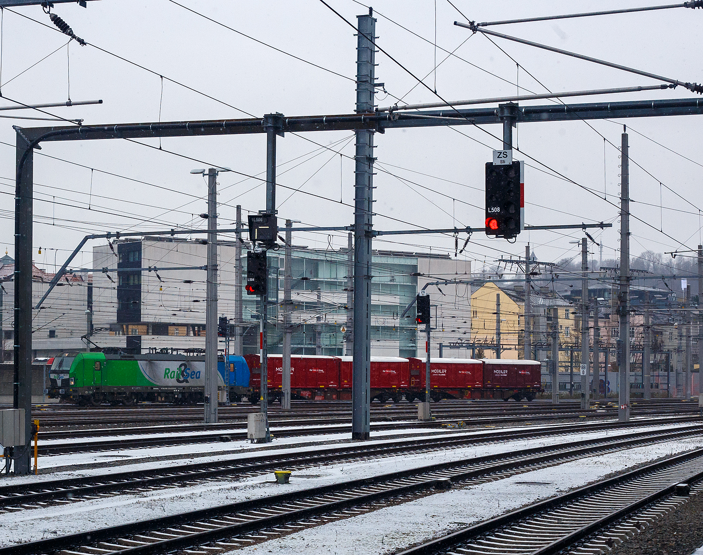 Die an die �sterreichische Rail&Sea Logistics GmbH (Seekirchen am Wallersee) Cargo vermietete SIEMENS Vectron MS 193 273-0 (91 80 6193 273-0 D-ELOC) der ELL - European Locomotive Leasing (Wien) f�hrt am 15 Januar 2025, mit einem kurzen Containerzug (2 Tragwagen beladen mit 4 MOBILER-Container der Rail Cargo Group), durch den Salzburg Hauptbahnhof in �stlicher Richtung. Leider steh ich hier auf dem Bahnsteig 1 und nicht auf 9, so sind einiger Masten dazwischen.

Die Multisystemlokomotive Siemens Vectron MS wurde 2016 von SIEMENS Mobilitiy in M�nchen-Allach unter der Fabriknummer 22034 gebaut. Sie wurde in der Variante MS A17 ausgef�hrt und hat so die Zulassungen f�r Deutschland, �sterreich, Polen, Tschechien, die Slowakei, Ungarn, Rum�nien, Slowenien, Kroatien und Bulgarien (D-A-PL-CZ-SK-H-RO-SL-HR-BG).  F�r Serbien (SRB) ist auch eine Zulassung vorgesehen, aber ist z.Z. noch durchgestrichen. 

So besitzt die Variante MS A17 folgende Zugsicherungssysteme: ETCS BaseLine 3, sowie f�r Deutschland (PZB90 / LZB80 (CIR-ELKE I)), f�r �sterreich (ETCS Level 1 mit Euroloop, ETCS Level 2, PZB90 / LZB80), f�r Polen (SHP, f�r Tschechien und Slowakei (LS (Mirel)), f�r Ungarn (ETCS Level 1, EVM (Mirel)), sowie f�r Rum�nien, Slowenien und Kroatien (PZB90