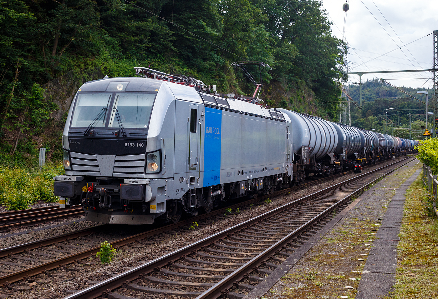 Die an die RTB Cargo vermietete SIEMENS Vectron MS 6193 140-1 (91 80 6193 140-1 D-Rpool) der Railpool GmbH in München fährt am 12 Juni 2024, mit einem Kesselwagenzug, durch Scheuerfeld/Sieg in Richtung Siegen. Laut den Gefahrgut- Warntafel 30/1202 waren die Wagen mit Dieselkraftstoff, Gas- oder Heizöl (leicht) beladen.

Die Multisystemlokomotive Siemens Vectron MS wurde 2023 von Siemens Mobilitiy in München-Allach unter der Fabriknummer 23363 gebaut. Sie wurde in der Variante A01 ausgeführt und hat so die Zulassung für Deutschland, Österreich, die Slowakei, Polen, Tschechien, Ungarn, Rumänien und Bulgarien  (D / A / SK / PL / CZ / H + RO / BG).
