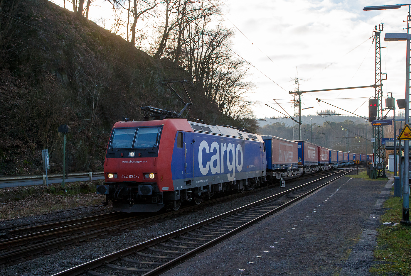 Die an die SBB Cargo International AG vermietete SBB Cargo Re 482 024-7 (91 85 4482 024-7 CH-SBBC) fährt am 28.01.2023 mit einem „Winner“ KLV-Ganzzug durch Scheuerfeld (Sieg) in Richtung Siegen.

Die TRAXX F140 AC1 wurde 2003 von Bombardier in Kassel unter der Fabriknummer 33590 gebaut und an die SBB Cargo AG geliefert. Sie hat die Zulassungen für die Schweiz und Deutschland. Wobei durch das fehlende ETCS ist der Einsatz in der Schweiz nur bedingt möglich, so sieht man sie hauptsächlich in Deutschland auf der Strecke zwischen Köln und Basel. Einige SBB Cargo Re 482 sind auch bereits verkauft worden.
