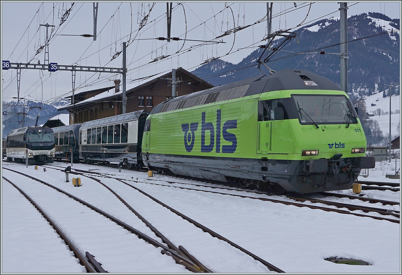 Die BLS Re 465 011 erreicht mit ihrem GoldenPass Express GPX 4065 von Interlaken Ost nach Montreux den Spurwechselbahnhof Zweisimmen. Im Hintergrund wartet die MOB Ge 4/4 8002 welche die Traktion des Zugs auf der schmalspurgien MOB übernehmen wird. 
Gleich hinter der Lok der sogenante  Interface -Wagen, nur auf dem Normalspurabschnitt mitgeführt wird und mit der Lok dann durch die  ausgeschaltete  Umspuranglage rollen wird.

15. Dezember 2022