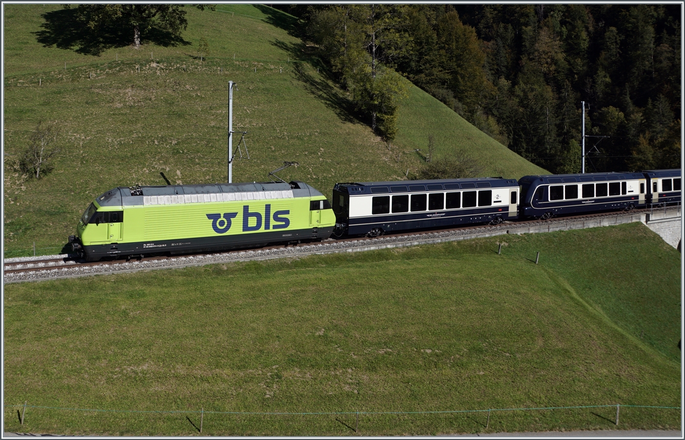 Die BLS Re 465 014 (UIC 91 85 4465 014-9) fährt mit ihrem GoldenPass Express GPX 4069 von Interlaken Ost nach Montreux bei Weissenburg bei der Bunschenbach Brücke. Das Motiv ist hier der Interface Wagen, der zwar optisch nicht so ganz passt, aber betrieblich sinnvoll ist. Er verkehrt grundsätzlich nur auf Normalspur, und dient dazu, die BLS Lok an den MOB Zug zu kuppelt. Zudem ist er ein willkommener Verstärkungswagen für Reisende von Interlaken nach Zweisimmen oder umgekehrt, dies insbesondere, da die GPX-Züge ziemlich strak ausgelastet sind.
Der Interfacewagen kann aus umgespurt werden und besitzt sogar Seite Montreux einen Führerstand, dies damit er für Unterhaltsabeiten nach Chernex überführt werden kann.

7. Okt. 2023