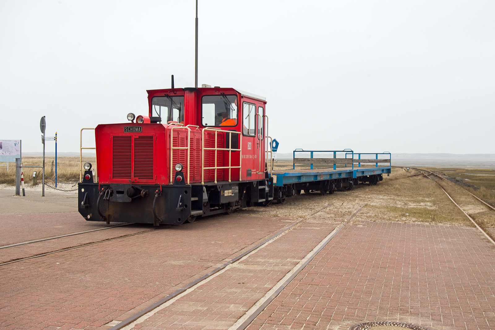 Die DB 399 108-0 (98 80 3399 108-0 D-DB) der Wangerooger Inselbahn (der DB Fernverkehr AG bzw. der SIW - Schifffahrt und Inselbahn Wangerooge) drückt am 12 März 2024 einen kurzen leeren Güterzug (zwei Flachwagen) vom Westanleger Wangerooge in Richtung zum Bahnhof Wangerooge. 

Die meterspurige Lok wurde 1999 von SCHÖMA - Christoph Schöttler Maschinenfabrik GmbH in Diepholz unter der Fabriknummer 5600 für die Inselbahn Wangerooge der Deutsche Bahn AG gebaut und geliefert.
