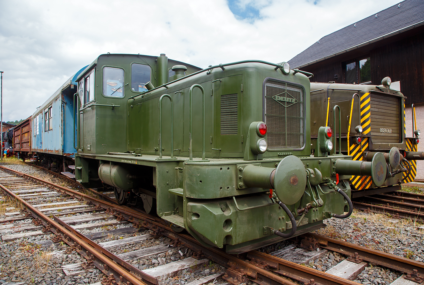 Die Deutz 57513 - eine DEUTZ  KS 230 B (A12L 714A) Diesellokomotive ehemals der Bundeswehr, am 02.07.2023 ausgestellt beim Erlebnisbahnhof Westerwald der Westerwälder Eisenbahnfreunde 44 508 e. V. hier war Lokschuppen-/Sommerfest. Die Lok ist Eigentum vom Militärhistorisches Museum Dresden und eine Leihgabe an die Eisenbahnfreunde. In der Lokstation Westerburg findet man eine einzigartige Spezialsammlung von Schienenfahrzeugen der Bundeswehr.

Die Lok wurde 1962 bei Deutz unter der Fabriknummer 57513 gebaut und an die BW (Fliegerhorstgruppe Erding) ausgeliefert, 2007 wurde sie außer Dienst gestellt.

Die Deutz Lokomotive KS 230 B (A12L 714A) ist die Weiterentwicklung der A12L 614 R und kam 1960 auf den Markt. In den folgenden Jahren wurde dieser Lokomotivtype in 44 Exemplaren gebaut. Alleine für die Bundeswehr wurden 21 Exemplaren geliefert. Die Osthannoverschen Eisenbahnen (OHE) bestellten drei Maschinen dieses Typs, die zudem über den gleichen Motorentyp hatten wie die Großraumtriebwagen der OHE, wodurch die Unterhaltung erleichtert wurde, auch war erforderlichenfalls ein Tausch möglich. Die bei den Bundeswehr-Loks eingebauten Motoren waren vom gleichen Typ, aber es waren luftgekühlte DEUTZ- Viertakt-Wirbelkammer-Vielstoffmotoren A12L 714 A. Sie konnten nicht nur mit Diesel, sondern auch mit etlichen anderen Kraftstoffen betrieben werden, arbeiteten aber im Diesel-Verfahren.

Die DEUTZ-Diesellok KS 230 B (A12L 714A) ist eine zweiachsige Rangierlokomotive mit hydraulischer Kraftübertragung und Stangenantrieb. Als Antriebsmotor wird der luftgekühlte DEUTZ-Vielstoffmotor A12L 714 A mit einer Leistung von 230 PS verwandt (bei zivilen Loks ein reiner Dieselmotor A12L 714). Die Motorleistung wird über eine Gummi-Dämpfungskupplung und Gelenkwelle auf das VOITH-Getriebe L 33 yUb übertragen. Von hier aus wird die Antriebskraft über das angeflanschte Wendegetriebe auf die zwischen den Achsen liegende Blindwelle weitergeleitet, die über Kurbeln, Treib- und Kuppelstangen beide Radsätze antreibt. 

Die Lokomotive hat ein Dienstgewicht von etwa 28 Tonnen und erreicht bei einer Zugkraft von 7000 kg auf gerader horizontaler Strecke eine Maximalgeschwindigkeit von 32 km/h. Der Kraftstoffverbrauch beträgt bei 50 % Durchschnittsbelastung um die 22 Kilogramm Dieseltreibstoff pro Stunde.

Am 19. Dezember 1961 wurde zwischen dem Bundesamt für Wehrtechnik und Beschaffung und der KHD AG, Köln-Deutz, der Hauptvertrag über die Lieferung von 21 Lokomotiven geschlossen. Die erste Maschine wurde am 28. Februar 1962 ausgeliefert.Diese Fahrzeuge waren für den Einsatz in Liegenschaften der Luftwaffe und Marine bestimmt. Sie erhielten die Versorgungsartikel-Bezeichnung:  Lokomotive, Vielstoff, 1.435 mm Spurbreite, 200 PS  und wurden der Versorgungsnummer 2210-12-137-0042 zugeordnet. Heute sind Loks vom diesem Typ im nationalen Fahrzeugregister als 98 80 3440...eingestellt.

Die Inbetriebsetzung der Maschinen bedeutete allerdings nicht für alle Fahrzeuge auch gleichzeitig den geplanten Einsatz. Viele bürokratische Hemmnisse, fehlende Infrastruktur und Betriebskostenrechnungen aus unterschiedlichster Betrachtungsweise führten dazu, dass Ende 1963 nur acht der Loks im planmäßigen Einsatz waren. Die übrigen dreizehn Loks standen unbenutzt an den einzelnen Standorten abgestellt. Mangelnde Erfahrung, nicht erfolgte Wartungen und mangelhafte Unterbringung der Fahrzeuge führten naturgemäß zu Störungen bei den nachfolgenden Inbetriebnahmen.

Der Ersatzteilservice, anstehende Reparaturen, sowie Frist- und Hauptuntersuchungen, wurden bis zur Einstellung der Lokomotivproduktion bei KHD Köln-Deutz, vom Lieferanten im Einzelauftragsverfahren vorgenommen. Ab 1972 übernahm die Firma Henschel & Sohn, Kassel die Wartung und Instandsetzung von Deutz - Lokomotiven. Das Bundesamt für Wehrtechnik und Beschaffung strebte allerdings zur Kostenreduzierung den Abschluss eines Instandhaltungs - Rahmenvertrages für alle Lokomotiven der Bundeswehr an. Es galt eine Werkstatt zu finden, die über das notwendige Know-How verfügte, um alle Arbeiten über die gesamte Palette der Bundeswehr - Lokomotiven fachgerecht auszuführen. In Moers wurde man fündig und so wurde am 09. Juli 1975 ein Vertrag zwischen der Firma MaK Kiel, Reparaturwerk Moers und dem BwB Koblenz geschlossen, der den gesamten Bestand von damals 50 regelspurigen Lokomotiven umfasste.

TECHNISCHE DATEN:
Typ:  KS 230 B
Spurweite: 1.435 mm (Normalspur)
Achsfolge: B  (zwei Achsen)
Länge über Puffer:   7.310 mm
Achsabstand: 2.650 mm
Treibraddurchmesser: 850 mm
Motor:  KHD luftgekühlter V12-Zylinder- Viertakt-Wirbelkammer-
Vielstoffmotor  vom Typ A12L 714 A (V-Winkel 90 Grad)
Motorhubraum: 19,0 l (Bohrung 120 mm x 140 mm Hub)
Leistung: 170 kW (230 PS) bei 2000 U/min
Leerlaufdrehzahl: 550 U/min
Einspritzpumpe: Bosch (110 bar)
Motorgewicht: ca. 1.300 kg
Motorabmessung: 1.670 x 1.222 x 920 mm
Getriebe: Voith L 33 yUb
Antriebübertragung: s.o.
Dienstgewicht:  28 t
Höchstgeschwindigkeit: 32 km/h (zivile Loks im Streckengang bis 54 km/h)
Raddurchmesser  850 mm
Anfahrzugkraft  9000 kg / 90 kN
Kraftstoffvorrat: 560 l
Sandvorrat: ca. 150 kg
Bremse:  Knorr Druckluftbremse

Quellen: http://www.bundeswehrloks.de/  http://www.erlebnisbahnhof-westerwald.de
