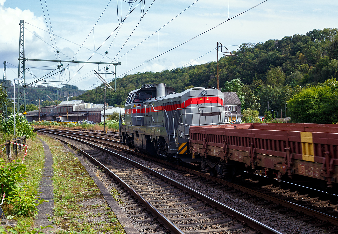 Die dieselhydraulische Vossloh G 12 – 4120 001-7 „Karl August“ (92 80 4120 001-7 D-KAF) der KAF Falkenhahn Bau AG (Kreuztal) fährt am 11 September 2024 mit Zug, bestehend aus leeren 4-achsiger Drehgestell-Flachwagen mit Seitenborden, Stirnwänden und Stahlfußboden, der Gattung Res-x 679.1 der DB Cargo AG, durch Scheuerfeld (Sieg) in Richtung Betzdorf (Sieg).
