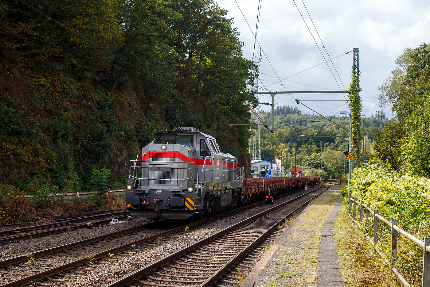 Die dieselhydraulische Vossloh G 12 – 4120 001-7 „Karl August“ (92 80 4120 001-7 D-KAF) der KAF Falkenhahn Bau AG (Kreuztal) fährt am 11 September 2024 mit Zug, bestehend aus leeren 4-achsiger Drehgestell-Flachwagen mit Seitenborden, Stirnwänden und Stahlfußboden, der Gattung Res-x 679.1 der DB Cargo AG, durch Scheuerfeld (Sieg) in Richtung Betzdorf (Sieg).

Übrigens, die Lok trägt den Namen des Firmengründers Karl August Falkenhahn, der die Baufirma 1919 in Kreuztal gründete. Die G12 wurde 2010 von Vossloh in Kiel unter der Fabriknummer 5001919, als Prototyp, gebaut und bereits auf der InnoTrans 2010 präsentiert, 2014 konnte ich sie selbst auf der InnoTrans 2014 als SLG Spitzke G 12 - SP - 012 (92 80 4120 001-7 D-VL) sehen und ablichten. Im Jahr 2017 wurde die Lok an die KAF Falkenhahn Bau AG (Kreuztal) verkauft. Aus Fachkreisen kann man hören dass es wohl nicht so ein guter Wurf war und so bleibt diese G 12 wohl ein Einzelstück. Lediglich von der diesel-elektrischen Variante (DE 12) wurden bisher 5 Stück gebaut. Die leistungsstärkere Serie G18 / DE 18 ist erheblich erfolgreicher.

Die G 12 wie auch die G 18 sind neue dieselhydraulische Lokomotiven der fünften Generation für den schweren Rangier- und Streckendienst von Vossloh Locomotives. Die G 12 mit 1.200 kW sowie die G 18 mit 1.800 kW. Angetrieben werden die Vierachser von den optimierten Turbo-Flex-Getrieben von Voith. Ein neues Drei-Wandler-Getriebe verbessert den Wirkungsgrad und ist mit einem leistungsfähigen Retarder zum verschleißfreien Bremsen ausgerüstet. Das Gesamtgewicht der Loks kann flexibel zwischen 80 und 90 t ausgelegt werden.

TECHNISCHE DATEN:
Spurweite: 1.435 mm (Normalspur)
Achsfolge: B‘B‘
Höchstgeschwindigkeit: 100 km/h
Dieselmotorleistung: max. 1.200 kW
Dieselmotor: MTU 8V 4000 R43 (L)
Dieselmotordrehzahl 1.800 min-1
Abgasvorschriften: EU/2004/26 Stufe IIIA/prepared for stage IIIB
Anfahrzugkraft: 259 kN
Dienstgewicht: 80 t
Raddurchmesser: 1.000 mm (neu) / 920 mm (abgenutzt)
Länge über Puffer : 17.000 mm
Größte Höhe: 4.310 mm
Größte Breite: 3.080 mm
Drehzapfenabstand: 8.100 mm
Achsabstand im Drehgestell: 2.400 mm
Strömungsgetriebe: Voith L 4r4 zseU2
Hydrodynamische Bremsleistung: max. 1.000 kW
Kleinster befahrbarer Bogenradius: 55 m
