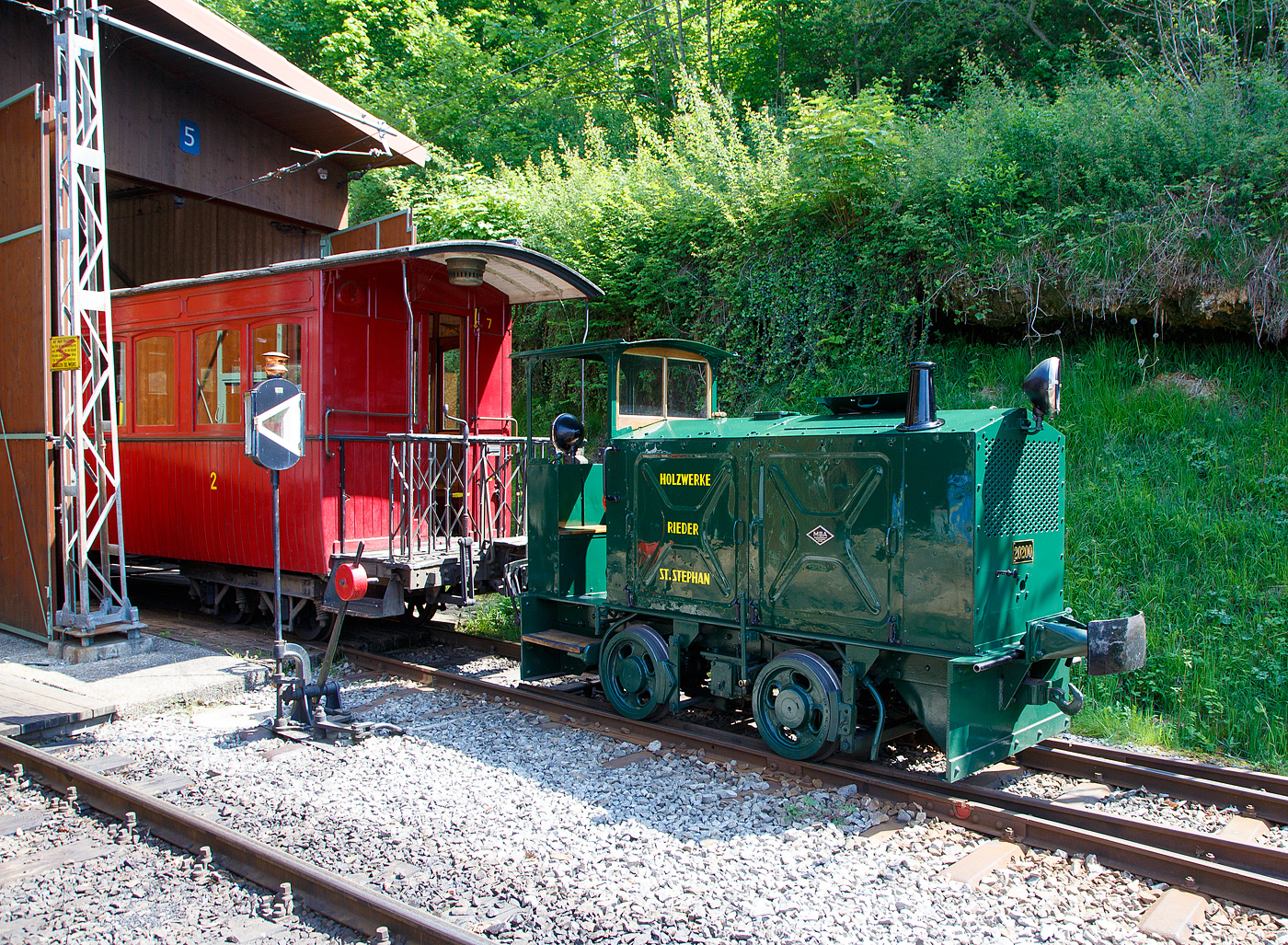 Die doch recht kleine ex MOB Schienentraktor Tm 2/2 Nr. 1, ex Holzwerk Rieder, der Museumsbahn Blonay-Chamby am 27.05.2023 im Museumsareal in Chaulin. 

Die kleine Diesellok, vom Typ O&K RL 2a wurde 1931 von Orenstein & Koppel im Werk Babelsberg unter der Fabriknummer 20200 gebaut und an die Grande Dixence SA für die Baustelle der ersten Dixence-Staumauer  geliefert, wo sie bis 1940 im Einsatz war. Im 1941 wurde sie dann von der Firma Mauerhofer & Zubner, für den Einsatz von Bauzügen beim Fahrleitungsumbau bei der MOB übernommen. 1950 wurde die kleine Lok an das Holzwerk Rieder in St. Stephan verkauft, diese Farbgebung trägt sie auch aktuell bei der BC. Die Lok trägt Fabrikschilder der MBA, wobei die Umbenennung der O&K in Maschinenbau und Bahnbedarf Aktiengesellschaft, vormals Orenstein & Koppel (MBA) erst im Februar 1940 erfolgte.

Die MOB (Montreux-Berner Oberland-Bahn / Montreux Oberland Bernois) kaufte die Lok dann 1979 wieder zurück und bezeichnete sie als Tm 2/2 1. Bei der MOB wurde sie für Rangierarbeiten, von Zementwagen auf Rollböcken in St. Stephan eingesetzt. Die Lok wurde 1995 von der MOB ausrangiert verbleib aber erst noch im Depot Montbovon. 2006 ging sie dann an die Museumsbahn Blonay-Chamby.

Die Lok hat einen 2-Zylinder-Orenstein & Koppel-Dieselmotor mit 22 PS (16 kW) Leistung, die Leistungsübertragung erfolgt über ein Zweigang-Konuskupplungs-Wendegetriebe mit stufenloser Geschwindigkeit Regulierung, über zwei Rollenketten auf die vordere Achse und von dieser über eine Rollenkette auf die hintere Achse. Das Zweigang-Konuskupplungsgetriebe ermöglicht zwei verschiedene Geschwindigkeitsstufen für beide Fahrtrichtungen. Dabei laufen immer beide Gänge im Eingriff, jeweils einer wird eingekuppelt. Eine einfache Wendeschaltung im Getriebe ermöglicht den Fahrtrichtungswechsel bei Stillstand der Lokomotive. Die einfache Bauart des Getriebes hat sich schon bei den Benzinloks bewährt und wurde bei fast allen O&K-Loks der unteren Leistungsklassen angewendet.

TECHNISCHE DATEN:
Spurweite: 1.000 mm (Meterspur)
Achsfolge: B
Länge über Puffer: 4.490 mm
Kastenlänge: 3.450 mm
Höhe: 2.270 mm
Breite: 1.240 mm
Achsabstand: 1.170 mm
Raddurchmesser : 550 mm
Eigengewicht: 7.000 kg
Leistung: 16 kW (22 PS)
Höchstgeschwindigkeit: 7 km/h
Achslager: Gleitlager

Die O&K Typenbezeichnung  RL  stand für  Rohöl  (= Diesel).

Anfang des 20. Jahrhunderts war es noch üblich bei und auf Großbaustellen Feld- oder Schmalspurbahnen zu bauen und zu betreiben. Heute durch Entwicklung von moderner und oft sehr schweren Baumaschinen und Muldenkipper eigentlich undenkbar.