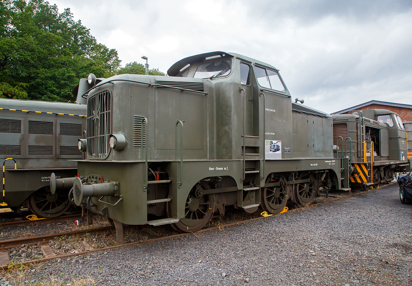 Die dreiachsige dieselhydraulische Henschel DH 360 ehem. der Bundeswehr ausgestellt am 03.07.2023 beim Lokschuppen vom Erlebnisbahnhof Westerwald der Westerwälder Eisenbahnfreunde 44 508 e. V. in Westerburg, hier war Lokschuppen-/Sommerfest.

Die Lok wurde 1956 von der Henschel-Werke GmbH in Kassel unter der Fabriknummer 28640 gebaut und an die Bundeswehr für das Materialübernahmegruppe Nord I in Hesedorf geliefert.

Die Henschel DH 360 C gehört zur 2. Generation (Buckel) der Henschel-Nachkriegslokomotiven. Sie hat einen langsam laufenden wassergekühlten 6-Zylinder-4-Takt-Reihendieselmotor vom Typ MWM RHS 335 S mit 360 PS Leistung bei 600 U/min. Die Kraftübertragung erfolgt vom Motor über eine elastische Kupplung auf das Flüssigkeitsgetriebe (Voith-Turbogetriebe der Type L 37U). Das Getriebe besteht aus einem hydraulischen Drehmomentwandler und zwei hydraulischen Kupplungen mit selbsttätig wirkender Steuerung. Diesem Getriebe ist ein kombiniertes Stufen- und Wendegetriebe nachgeschaltet, in dem auch die Blindwelle gelagert ist. Von der Blindwelle aus werden die drei Radsätze mit Treib- und Kuppelstangen angetrieben.

Für das Anlassen des Motors, das mittels Druckluft erfolgt, sind zwei Luftflaschen mit je 250 Liter vorhanden. Die Kühlanlage besteht aus dem Wasserkühler, dem Getriebeölkühler, dem Kühler für das Motorschmieröl und dem Lüfterrad. Die Lok besitzt außer der 6-Klotz - Handspindelbremse eine durchgehende Druckluftbremse für Lokomotive und Zug sowie eine Druckluftzusatzbremse für die Lokomotive allein. Die Beleuchtungsanlage der Lok wird aus einer Batterie gespeist, die durch eine ständig vom Motor angetriebene Lichtmaschine geladen wird. Die Lokomotive hat ein Dienstgewicht von 41,2 Tonnen und erreicht auf gerader horizontaler Strecke im Verschiebedienst eine Maximalgeschwindigkeit von 30 km/h, sowie im Streckendienst von 60 km/h. Bei der Bundeswehr erhielt dieser Loktyp die Versorgungsnummer 2210-12-121-8552.

Da diese Lokomotive hier ist die zu allererst an die Streitkräfte gelieferte Maschine ist, war deren Erhaltung schon aus historischer Sicht ein Muss. Die Lok, unter Eisenbahnfreunden auch als  Buckel-Henschel  bezeichnet, ist derzeitig nicht betriebsfähig. Die Lok ist Eigentum vom Militärhistorisches Museum Dresden und eine Leihgabe an Westerwälder Eisenbahnfreunde 44 508 e. V.

TECHNISCHE DATEN:
Spurweite: 	1.435 mm (Normalspur)
Achsfolge: C 
Länge über Puffer: 9.440 mm
Treibraddurchmesser: 1.150 mm (neu)
Eigengewicht: 40 t
Dienstgewicht: 41,2 t
Höchstgeschwindigkeit: 30 km/h (Rangiergang) / 60 km/h (Streckengang)
Motorentyp: MWM RHS 335 S
Motorbauart:  wassergekühlten 6-Zylinder-4-Takt-Reihendieselmotor
Motorhubraum: 40 Liter
Installierte Leistung: 265 kW (360 PS) 
Nenndrehzahl:  600 U/min.
Leistungsübertragung: hydraulisch
Getriebe: Voith-Turbo-Getriebe L 37 U
Anfahrzugkraft: 12.000 kg / 117,7 kN
Bremse: Knorr Druckluftbremse m.Z.

Geschichte:
Die Firma Henschel & Sohn Kassel entwickelte nach Freigabe des Lokomotivneubaus durch die Alliierten die neue DH-Serie, die wegen ihres äußeren auch “Möbelwagen” genannt wurde. Konstruktiv hatte diese Serie wenig Neues zu bieten, waren die Maschinen doch lediglich Wehrmachtsloks mit neuem Lokaufbau.

Bereits Ende 1953 hatte Henschel eine neue Typenfamilie der Bauart DH mit hochliegenden Mittelführerständen konzipiert. Die Produktion dieser Übergangsserie wurde im Frühjahr 1953 aufgenommen. Die Maschine der Bundeswehr, DH 360 C Baujahr 1956, entstammt dieser Typenreihe, sie erhielt die Versorgungsnummer 2210-12-121-8552.

Am 19. April 1956 übernahm die Deutsche Bundeswehr mit der Henschel Lok DH 360 C ihre erste eigene Lokomotive. Die Inbetriebnahme der unter der Werknummer 28640 gefertigten Maschine wurde am gleichen Tag beim Gerätepark Hesedorf vorgenommen. Obwohl die Firma Henschel & Sohn nicht zum Kreis der vom Bundeskanzleramt Koblenz, Abteilung V D 4, mit Schreiben vom 13.12.1954 zum Angebot aufgeforderten deutschen Lokomotivhersteller gehörte, beteiligten sich die Kasseler Lokomotivbauer an der Ausschreibung. Wieder einmal bewahrheitete sich, dass die Letzten die Ersten sein würden, denn noch im Jahr 1955 wurde der erste Liefervertrag für eine Bundeswehrlokomotive abgeschlossen. Die Kaufsumme der Lokomotive betrug DM 346.020,-- inklusive der 1955 noch 4% betragenden Umsatzsteuer.

Nach der Abnahme in Hesedorf wurde die Lokomotive zur Dienstleistung an das Munitionsdepot Walsrode - Beetenbrück versetzt. An diesem Standort wurde die Lok bis 1985 im Verschiebedienst eingesetzt. Weitere Einsätze führten die Lok über das Gerätedepot Glinde zum Munitionsdepot Boostedt. Zum Weihnachtsfest 1994 sollte die Lokomotive am ,,Aufbau OST  im Gerätehauptdepot Lohmen teilnehmen. Bei der Überführungsfahrt trat allerdings das Wandlergetriebe in den Ausstand, wodurch erst ein neuerlicher Besuch in Moers erforderlich wurde. Im Februar 1995 traf DH 360 als ,,Militärverkehr-Deutsche Bundeswehr  im Schlepp einer DB-Lok in der MaK/Siemens-Werkstatt ein. Da die Lok nun schon einmal in Moers war, entschied der zuständige Güteprüfer der WBV auch gleich eine vollständige Hauptuntersuchung vornehmen zu lassen. Am 23. August 1995 übernahm dann das Lokpersonal aus Lohmen die Lokomotive in Moers und überführte sie zur neuen Dienststelle in die Sächsische Schweiz. Dieser Einsatz währte bis zu Schließung des dortigen Depots Mitte des Jahres 1997und endete mit der Versetzung zum Gerätehauptdepot Zeithain. Nach einem Motorschaden im Dezember 1998 musste die Lok abgestellt werden, da eine Instandsetzung vor Ort nicht möglich war wurde sie im Mai 1999 wieder nach Moers transportiert. Den Jahrtausendwechsel verbrachte unsere DH 360 am Niederrhein, bevor es Anfang Februar 2000 wieder zurück ins Land der Sachsen ging. Dank der Besonderheiten des Vertrages zur Deutschen Einheit konnte die Lokomotive noch über die in den alten Bundesländern gültigen Fristgrenzen bis 2003 eingesetzt werden.

Zwischenzeitlich hatte jedoch die Deutsche Bahn AG die Bedienung des Standortes Zeithain eingestellt, fortan erreichten die Frachtsendungen Zeithain ab Riesa per LKW. Dadurch war die Lok arbeitslos geworden. Nachdem man sich 2004 mit der DBAG zu einer Wiederaufnahme der Bedienung des Bundeswehr - Anschlusses entschlossen hatte, wurde die z-gestellte DH 360 durch eine KHD KS 230 B abgelöst.

Das Schicksal dieser historisch wertvollen Maschine schien besiegelt, es folgte die Aussonderung und es war nur noch eine Frage der Zeit, wann die Verwertung durch Verschrottung erfolgen würde. Bei einen Besuch in Zeithain im Herbst 2007 wurde die Lok in einem optisch und technisch ansprechenden Zustand vorgefunden, sodass der Wunsch entstand, die Lok in die ,,Spezialsammlung Bundeswehr - Eisenbahn  in Westerburg aufzunehmen.

Das Militärhistorische Museum Dresden befürwortete dieses Ansinnen und übernahm die  Nummer 1  der Bundeswehr in den Museumsbestand. Am 08. August 2008 erreichte die Henschel Lokomotive auf einem Tieflader der Firma Goll den Erlebnisbahnhof Westerburg. Per Leihvertrag wurde sie der Sammlung im Erlebnisbahnhof Westerburg übergeben, wo sie nun nach einem wahrlich bewegten über 50-jährigen Einsatzzeitraum behütet und gepflegt der Öffentlichkeit zugänglich ist.
