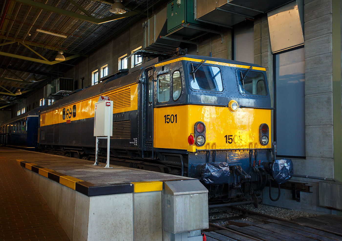 Die Elektrolokomotive NS 1501 „Diana“, ex BR E27003 „Diana“, am 29 April 2025 im Het Spoorwegmuseum (bis 2005 NSM - Nederlands Spoorwegmuseum / Niederländischen Eisenbahnmuseum) in Utrecht im Bahnhof Maliebaanstation. Ein Eisenbahnmuseum das zum Verweilen einlädt, leider fehlte uns dieses Mal die Zeit dafür.  

Die Lok wurde 1954 von den Gorton Locomotive Works in Manchester (GB), mit der elektrischen Ausrüstung von Metropolitan Vickers in Manchester, gebaut und an die BR - British Railways (heute British Rail) als 27003 „Diana“, ab 1957 wurde sie als BR E27003 „Diana“ geführt. Im Jahr 1969 kaufte die NS - Nederlandse Spoorwegen (Niederländischen Staatsbahnen, heute Niederländische Eisenbahnen AG) alle 7 Loks der British Rail Class 77. Die dann als Serie NS 1500 geführt wurden. Wobei nur 6 Loks bei der NS zum Einsatz kamen, die ex BR E27005 „Minerva“ diente als Ersatzteilspender, der Rest von ihr wurde bereits im November 1969 verschrottet. 

Die Reihe 1500 der Nederlandse Spoorwegen (NS) ist eine Baureihe von 6 Stück gebrauchten sechsachsigen Elektrolokomotiven für den schweren Schnellzugdienst, die von 1953 bis 1954 bei den Gorton Works in Manchester als Klasse EM2 für die British Railways gebaut, später als Klasse 77 bezeichnet wurde. Bei der British Railways (heute British Rail) wurden die Loks  für Personen-Schnellzüge auf der, mit 1,5 kV DC elektrifizierten, Woodhead-Linie zwischen Manchester und Sheffield eingesetzt. Da die British Rail den Personenverkehr auf der Woodhead-Linie im Januar 1970 einstellte, wurden die Loks der Baureihe 27000 ab September 1968 vom Einsatz abgezogen nach Bury gebracht und eingelagert, in der Hoffnung auf einen Verkauf an eine ausländische Bahn. Wenig später, im August 1969, inspizierten niederländische Beamte der NS die BR E27002, mit der sie dann eine Testfahrt zwischen Sheffield und Reddish durchführten. Die NS war so beeindruckt, die einen akuten Lokmangel hatte, dass sie alle sieben Lokomotiven kauften. 

Die NS hatte bereits einige Jahre zuvor an der Entwicklung einer neuen 1400er-Serie gearbeitet, musste dies jedoch aufgrund der hohen Kosten einstellen. Da der Bedarf der NS an Lokomotiven immer weiter stieg, kam man schließlich zur englischen Baureihe 27000. Es handelt sich um die erste und bislang einzige Serie, die gebraucht erworben wurde. 

Die BR-Loks wurde im September 1969 mit der Fähre von Harwich nach Zeebrugge (Seebrügge) in die Niederlande verschifft. Sie wurden dann zu den NS-Werkstätten in Tilburg gefahren, wo Umbauten und Generalüberholungen stattfanden. Zu den Umbauten gehöhrten neue Spitzenlichter, neue andere Pantographen (Einholmstromabnehmer), sowie ein neues Bremssystem. Auch die Führerstände wurden umgebaut, der Führertisch wurde von der linken Seite nach rechts verlegt. 

Die gesamte Serie wurde in die niederländische Serie 1500 um nummeriert, mit Ausnahme einer Lokomotive, der BR E27005 „Minerva“, sie galt als über eine wirtschaftliche Reparatur hinaus und wurde infolgedessen als Ersatzteilspender verwendet. Auf die 1400er-Nummern wurde bewusst verzichtet. Die Engländer hatten allen Lokomotiven außerdem Namen gegeben, die auf weiblichen Figuren aus der römischen Mythologie basierten. Diese Namen wurden beibehalten und daher ist die 1501 auch als Diana bekannt.

Die Lok bekamen nach der Reihenfolge der Generalüberholung ihre neuen NS-Bezeichnungen. Die ex BR E27003 „Diana“ war die erste generalüberholte Lok, so wurde aus ihr die NS 1501 „Diana“. Sie war zugleich die erste Elektrolokomotive, die in der neuen Hausfarbgebung Gelb/Grau auf die Strecke kam. In den Niederlanden waren die 6 Lokomotiven bis 1985/1986 in Betrieb.

TECHNISCHE DATEN:
Hersteller (mech.): Gorton Locomotive Works in Manchester (GB)
Elektrischen Ausrüstung: Metropolitan Vickers in Manchester
Baujahre: 1953 / 1954
Ausmusterung: bei BR 1969 / bei NS 1985/1986
Gebaute Anzahl: 7 (bei der NS 6 im Einsatz, 1 als Ersatzteilspender)
Nummerierung: 	NS 1501 bis 1506
Spurweite: 1.435 mm (Normalspur)
Achsfolge: Co’Co’ 
Länge über Puffer: 17.983 mm
Treibraddurchmesser: 1.092 mm (neu)
Dienstgewicht: 98 t (nach Umbau, bei BR 102 t)
Antriebsmotoren: 6 Stück (von Metropolitan Vickers)
Höchstgeschwindigkeit: 140 km/h 
Stundenleistung: 1.860 kW (2.520 PS)
Anfahrzugkraft: 200 kN
Bremskraft: 850 kN
Stromsystem: 1,5 kV DC (=)
