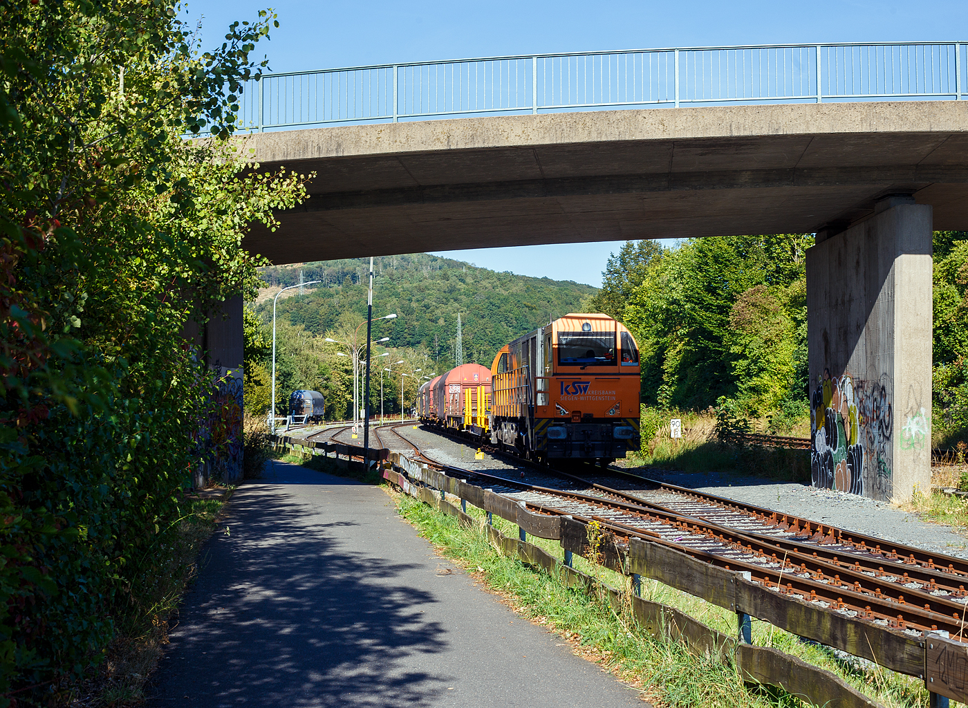 Die KSW 43 (92 80 1273 018-2 D-KSW), die asymmetrische Vossloh G 2000 BB (Ursprungsausführung) der KSW (Kreisbahn Siegen-Wittgenstein) steht am 27 August  2024, mit einem Übergabegüterzug (leere Wagen) abgestellt in Herdorf auf dem Rbf der Kreisbahn Siegen-Wittgenstein (KSW).

Die Lok 43 der KSW wurde 2002 von Vossloh Locomotives GmbH (VSFT/MaK Lokomotiven) in Kiel unter der Fabriknummer 1001327 gebaut und an die noch damalige SK - Siegener Kreisbahn GmbH als SK 43. Zum 23.12.2004 firmierte die SK in die heutige KSW - Kreisbahn Siegen-Wittgenstein GmbH um. 
