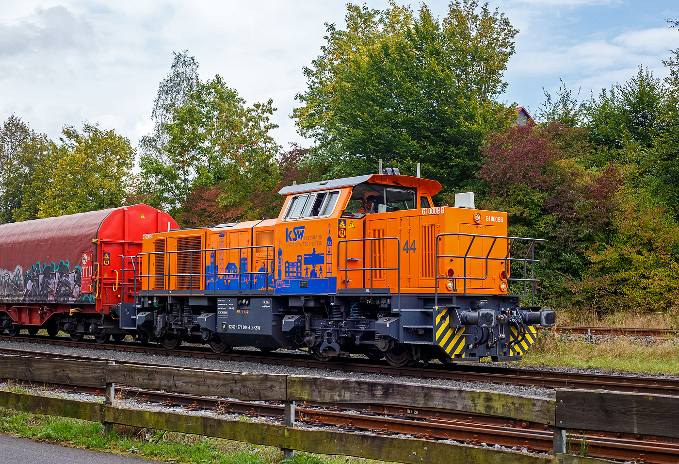 Die KSW 44 (92 80 1271 004-4 D-KSW) eine MaK G 1000 BB der KSW (Kreisbahn Siegen-Wittgenstein), steht am 02 Oktober 2024 mit einem Übergabezug (leere Wagen), auf ihren Rangierbahnhof in Herdorf der Betriebsstätte FGE -Freien Grunder Eisenbahn (KSW NE447 / DB-Nr. 9275), , zur Abfahrt bereit. 

Die Lok 44 wurde 2003 unter der Fabriknummer 1001462 bei Vossloh gebaut und am 05.01.2004 an die SK - Siegener Kreisbahn GmbH geliefert, welche ab Ende 2004 nun als Kreisbahn Siegen-Wittgenstein (KSW) firmiert.