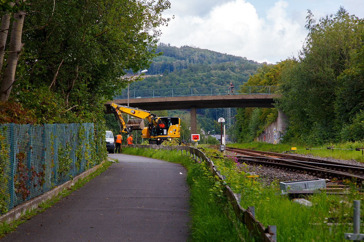 Die KSW (Kreisbahn Siegen-Wittgenstein) erneuert die ersten Gleismeter vom Anschlussgleis, zum Rangierbahnhof in Herdorf der Betriebsstätte FGE -Freien Grunder Eisenbahn (KSW NE447 / DB-Nr. 9275).

Hier am 16.08.2023 im Einsatz der Caterpillar CAT M323F Zweiwegebagger mit hydrostatischem Schienenradantrieb (Serien-Nr. RH600 189), Kleinwagen Nr. D-ZBM 99 80 9902 521-0 der ZEPPELIN Baumaschinen GmbH (Garching), ein Mietbagger vermietet an die Firma  W. Hundhausen Bauunternehmung GmbH (Siegen). Es werden die ersten Gleismeter vom Anschlussgleis erneuert, der Bagger ist bei der Einschotterung.
