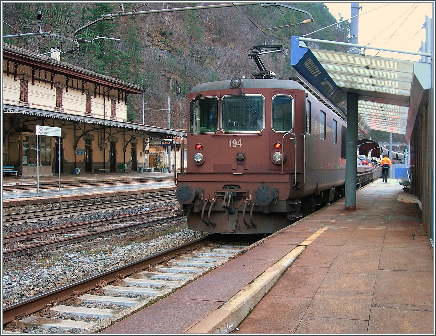 Die Mitte Dezember aus Witterungsgr�nden (Erdrutschgefahr) verschoben Reise konnte ich nun nachholen und so ist aus der  letzten Reise 2023 nach Italien  die  erste Reise nach Italien im neuen Jahr 2024  geworden. Anzumerken ist, dass die  Reise nach Italien  mit nur gut 50 Minuten mehr als kurz war...

Der langen Rede kurzer Sinn: durch ein Zaunschlupfloch in Iselle konnte ich mit meiner alten Knipse die BLS Re 4/4 194 mit ihrem AT3 (Autotunnelzug Birg - Iselle) fotografieren und auch gleich noch ein Teil der Empfangsgeb�udes von Iselle im linken Bildteil dazunehmen.
Trotzt blauem Himmel, der sich hier nur �berbelichtet rosa zeigt, scheint die Sonne um diese Jahreszeit den Weg ins tiefe Tal nicht zu finden.   

3. Januar 2024