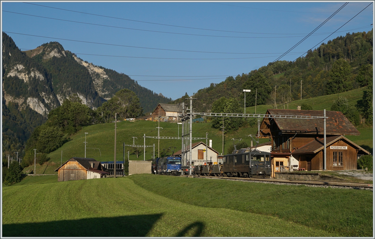 Die MOB Ge 4/4 8001 erreicht mit ihrem GoldenPass Express GPX 4064 von Montreux nach Interlaken Ost den Bahnhof von Rossinière. Und fährt auf Gleis 3 druch den Bahnhof, während auf Gleis 2 die GDe 4/4 6002 mit ihrem Güterzug auf die Weiterfahrt in Richtung Montreux wartet. 

29. Sept. 2023