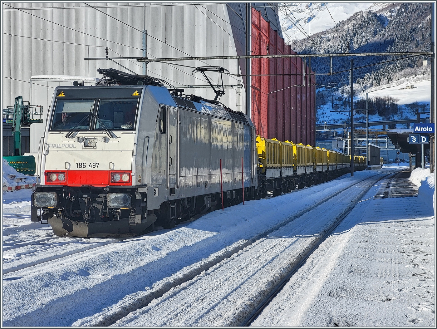 Die Railpool 186 497 ist mit ihrem aus Sggrrs S 204 Wagen bestehenden Ganz-G�terzug in Airolo angekommen. Die Wagen werden in der Folge unter die Beladungseinrichtung (links im Bild) rangiert und beladen. 

21. Jan. 2025