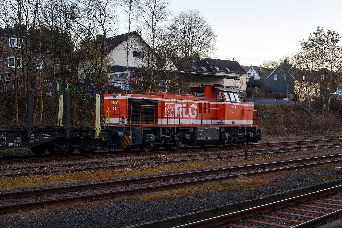 Die RLG 54 / 175 504-9 (92 80 1275 504-9 D-RLG) eine MaK G 1206 der RLG - Regionalverkehr Ruhr-Lippe GmbH (Soest), vermietet ans Schwesterunternehmen WLE - Westfälische Landes-Eisenbahn GmbH, kommt am 18. März 2025 auf ihrer Heimreise mit einem leeren Güterzug (Schwerlastwagen) von der Salzgitter Mannesmann Precision GmbH in Burbach-Holzhausen über die Hellertalbahn durch Herdorf. Hier im Bahnhof Herdorf hat sie, wegen der eingleisigen Strecke, erstmal Hp 0, bevor es in Richtung Betzdorf weitergeht.

Die G 1206 wurde 2008 von Vossloh in Kiel unter der Fabriknummer 5001638 gebaut. Sie war die erste wieder mit einen MTU gebaute G 1206. So hat sie einen wassergekühlten V12-Zylinder-Dieselmotor mit Abgasturbolader und Ladeluftkühlung vom Typ MTU mit einer Leistung von 1.500 kW (bei 1.800 U/min).

TECHNISCHE DATEN der G 1206:
Spurweite: 1.435 mm
Antriebart:  dieselhydraulisch
Achsfolge: B'B' 
Länge über Puffer: 14.700 mm
Drehzapfenabstand: 7.200 mm
Achsabstand im Drehgestell: 2.400 mm
größte Breite: 3.080 mm
Höhe über Schienenoberkante: 4.220 mm
Raddurchmesser neu: 1.000 mm
Motor: MTU 12 Zylinder 4-Takt Dieselmotor mit Abgasturbolader und Ladeluftkühlung vom Typ 12V 4000 R41
Leistung: 1.500 kW bei1.800 U/min
Strömungsgetriebe: Voith L 5r4 zseU2
Anfahrzugkraft: 267 kN
Höchstgeschwindigkeit: 100 km/h
kleinster befahrbarer Gleisbogen:	60 m
Dienstgewicht: 88 t
Kraftstoffvorrat: 3.150 l