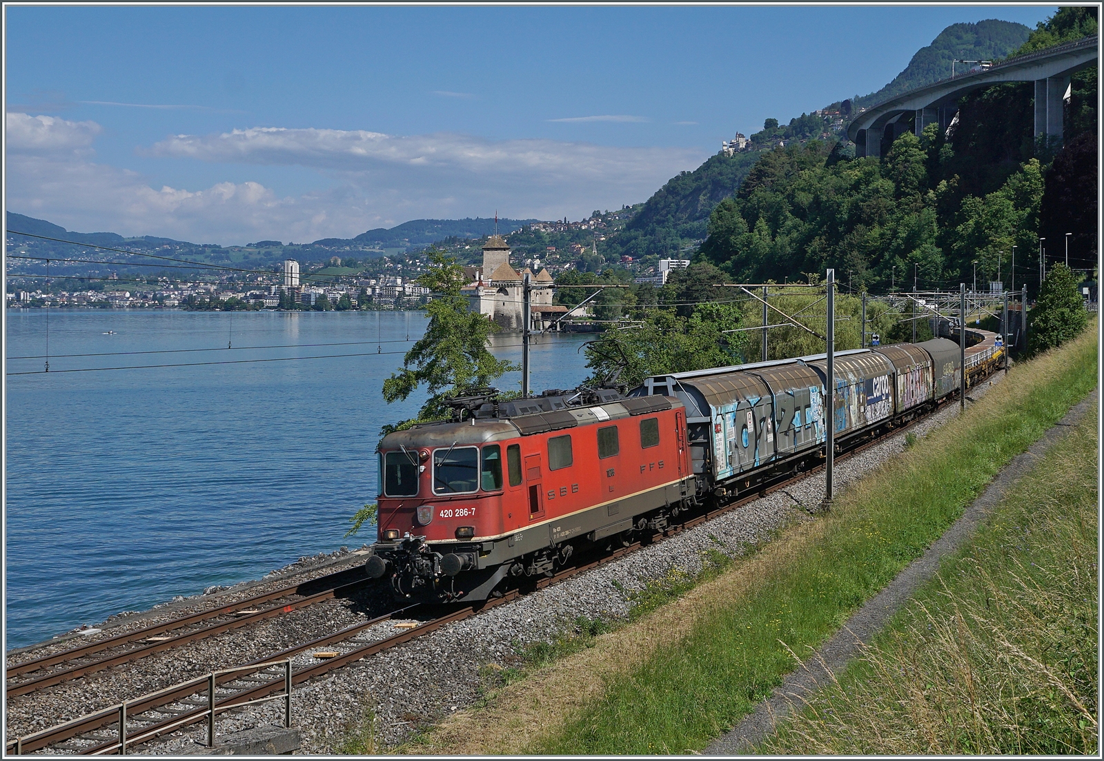 Die SBB Re 4/4 II 11286 (Re 420 286-7) ist kurz vor Villeneuve mit einem Güterzug unterwegs. Im Hintergrund ist das Château de Chillon zu sehen. 

5. Juni 2024