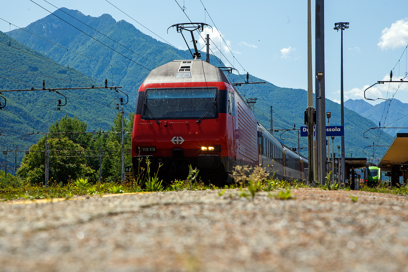 Die SBB Re 460 016-0  Rohrdorferberg Reusstal   (91 85 4 460 016-0 CH-SBB) hat am 26 Mai 2023 mit dem IR 3017 (Brig – Domodossola) den Zielbahnhof Domodossola (I) erreicht und ist nun mit dem Zug auf Gleis 6 abgestellt. Nach gut 2 ½ Stunden (um 13:48 Uhr) geht es dann als IR3022 von Domodossola zur�ck nach Brig.

Die Lok2000 wurde 1992 von der SLM (Schweizerischen Lokomotiv- und Maschinenfabrik in Winterthur) unter der Fabriknummer 5477 gebaut, der elektrische Teil ist von der ABB (Asea Brown Boveri). Sie war 2015 der 2. Prototyp der im SBB Werk Yverdon-les-Bains (VD) das vollst�ndige Modernisierungs-/Refit-Programm LOK2000 durchlief. So sollen die Loks fit f�r die n�chsten 20 Jahre sein, zudem werden durch alle 119 SBB Re 460 Lokomotiven so etwa 30 Gigawattstunden Energie eingespart.