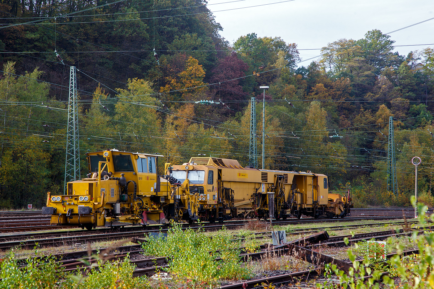 Die SSP 911 eine Deutsche Plasser  Schnellschotterplaniermaschine SSP 110 SW (Schweres Nebenfahrzeug Nr. D-DB 99 80 9425 077-1, ex 97 16 40 065 18-3), der DB Bahnbau Gruppe und dahinter die USM 641“Ruhpott“ eine Matisa Universal-Stopfmaschine B 66 U – D2 (einschl. Schotter-Kehrbürste am Anhänger)  der DB Bahnbau Gruppe (Schweres Nebenfahrzeug Nr. D-DB 99 80 9424 026-9, ex 97 43 38 002 17-9), ex DB Netz AG, sind am 29.10.2022 in Betzdorf (Sieg) abgestellt.